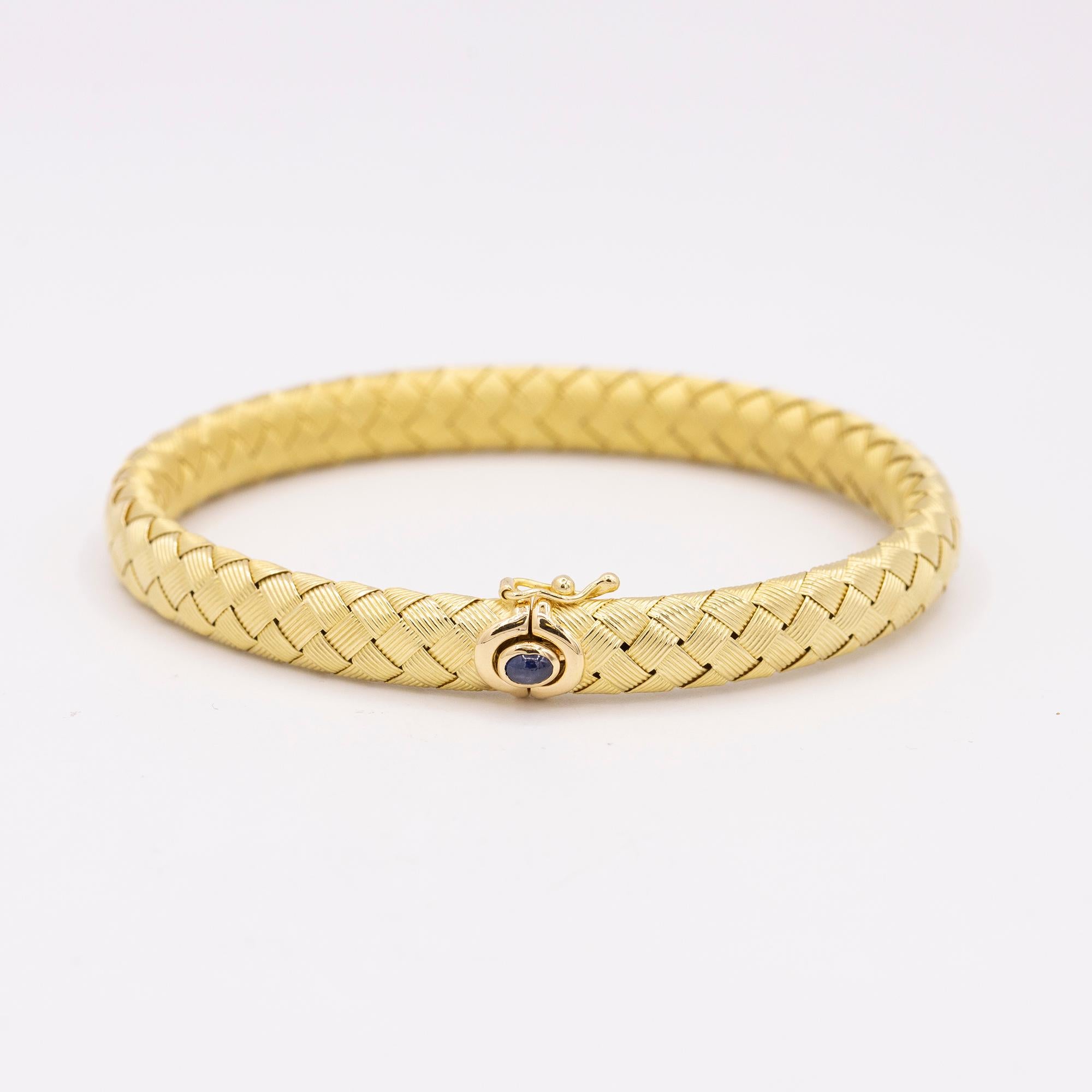 18 karat yellow gold braided bracelet with flexible construction with blue cabochon sapphire.

