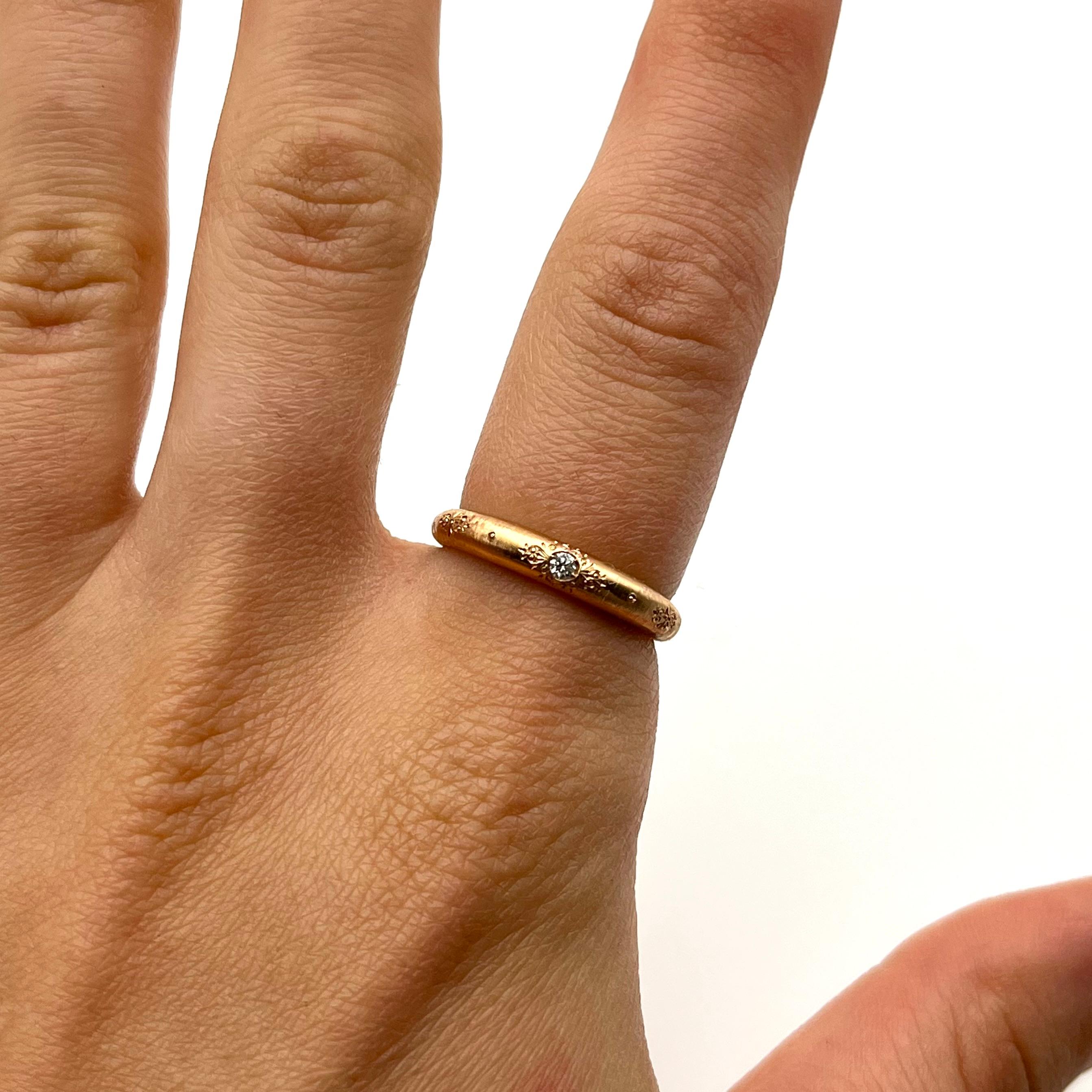 This sweet band was handmade by a family jeweler outside of Florence, Italy. It is set in solid 18-karat rose gold and each line is individually etched. It features one, full-cut round diamond that is set flush to the band. The stone weighs .02