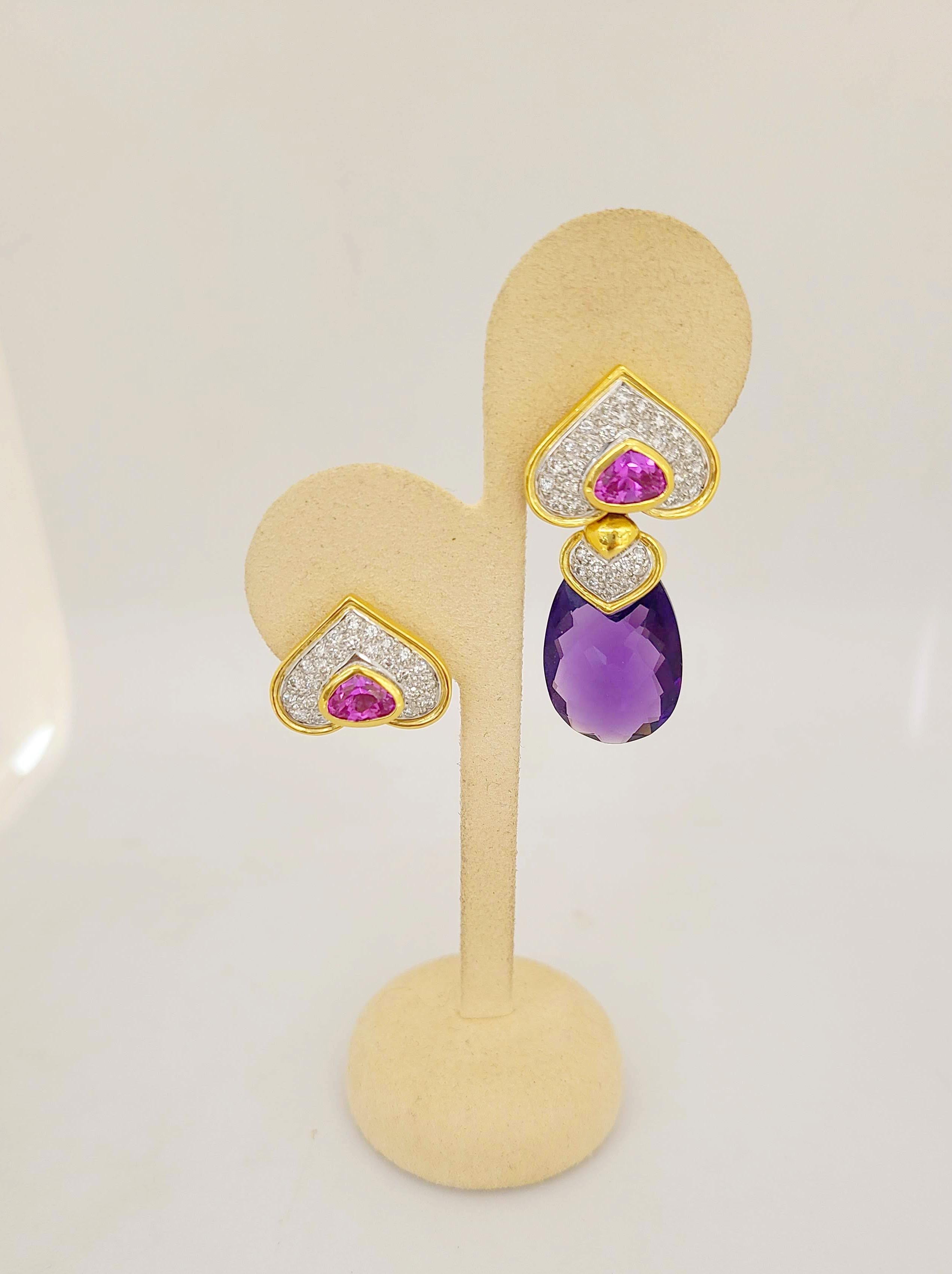 These earrings are designed with 18 karat yellow gold heart shapes that have been pave set with diamonds. A single heart shaped bezel set pink tourmaline is in the center of each heart. A detachable diamond capped amethyst drop hangs from the gold