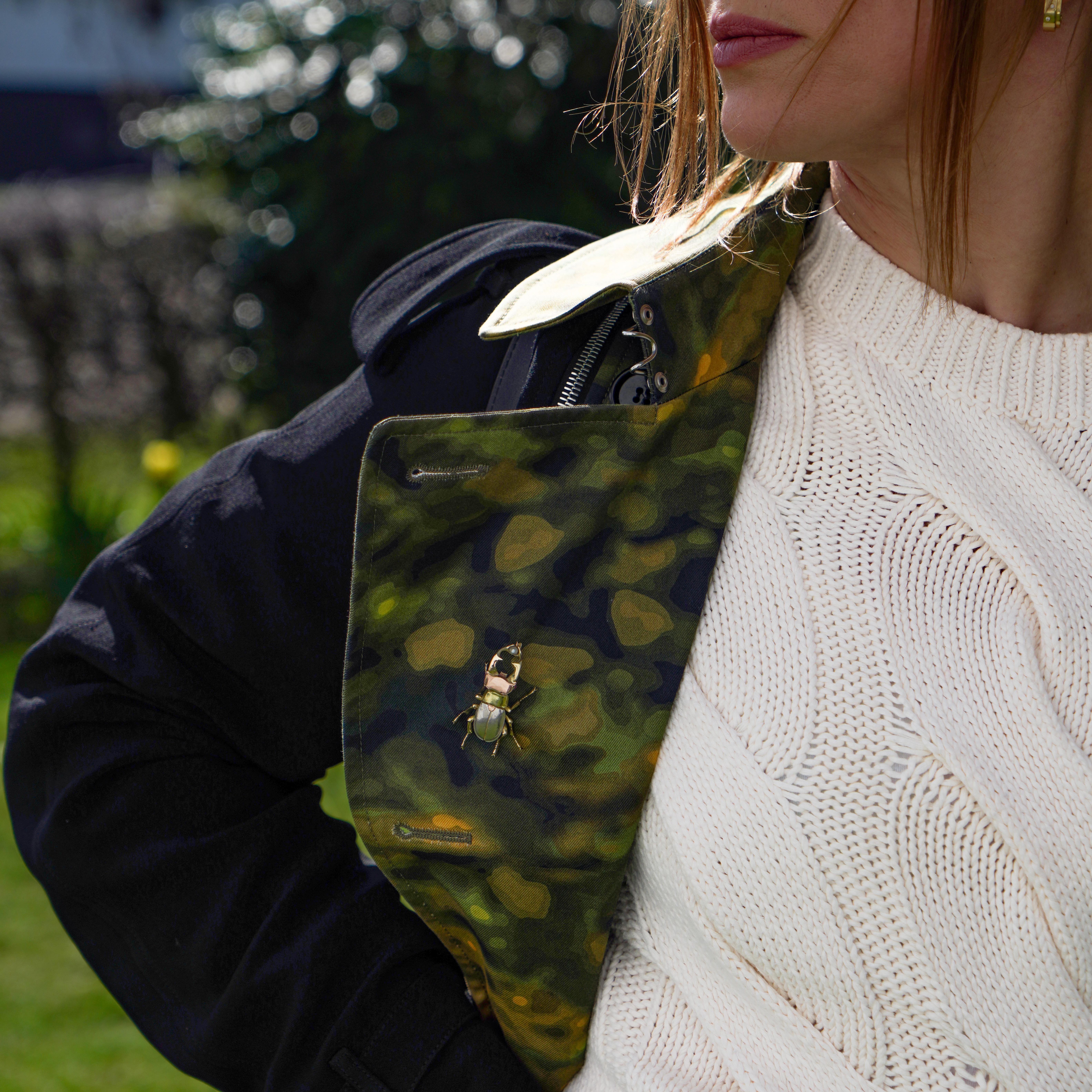 Un broche de escarabajo finamente elaborado en oro de 18 quilates y platino, diseñado con una forma realista muy detallada. Este exquisito broche es una representación de un escarabajo ciervo, con patas texturadas, cuerpo detallado y mandíbulas