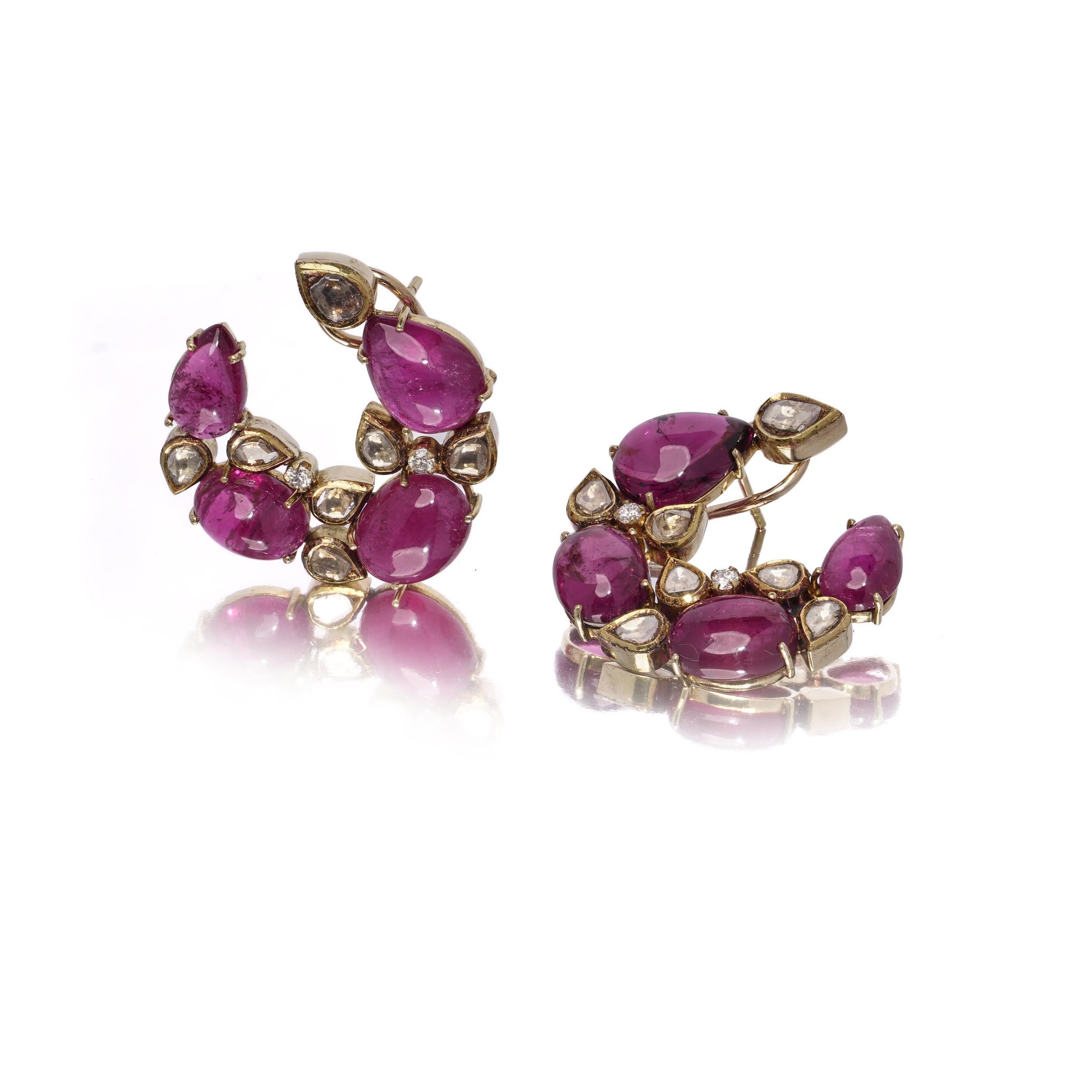 A bold and elegant pair of earrings crafted in 18kt yellow gold, set with richly coloured cabochon pink tourmalines and an artistic mix of brilliant and rose-cut diamonds. The design features a swirling, botanical-inspired form with organically