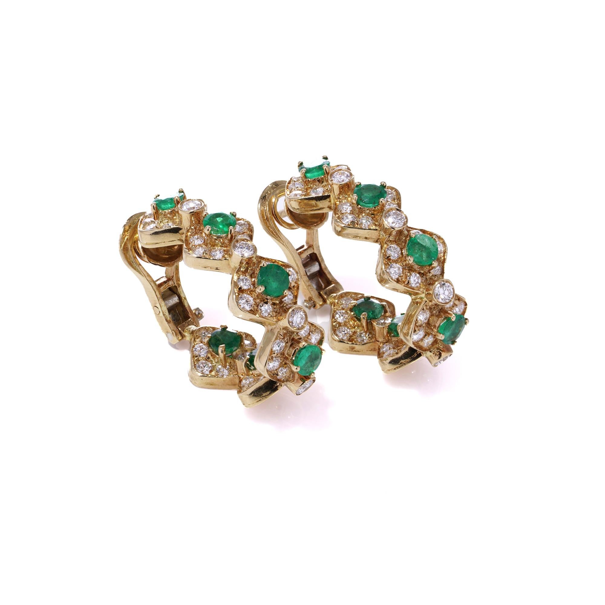 A pair of vintage clip-on earrings crafted in the 1990s from 18kt yellow gold. These earrings feature an elegant wavy geometric design showcasing a striking combination of natural emeralds and round brilliant-cut diamonds. Each emerald is carefully
