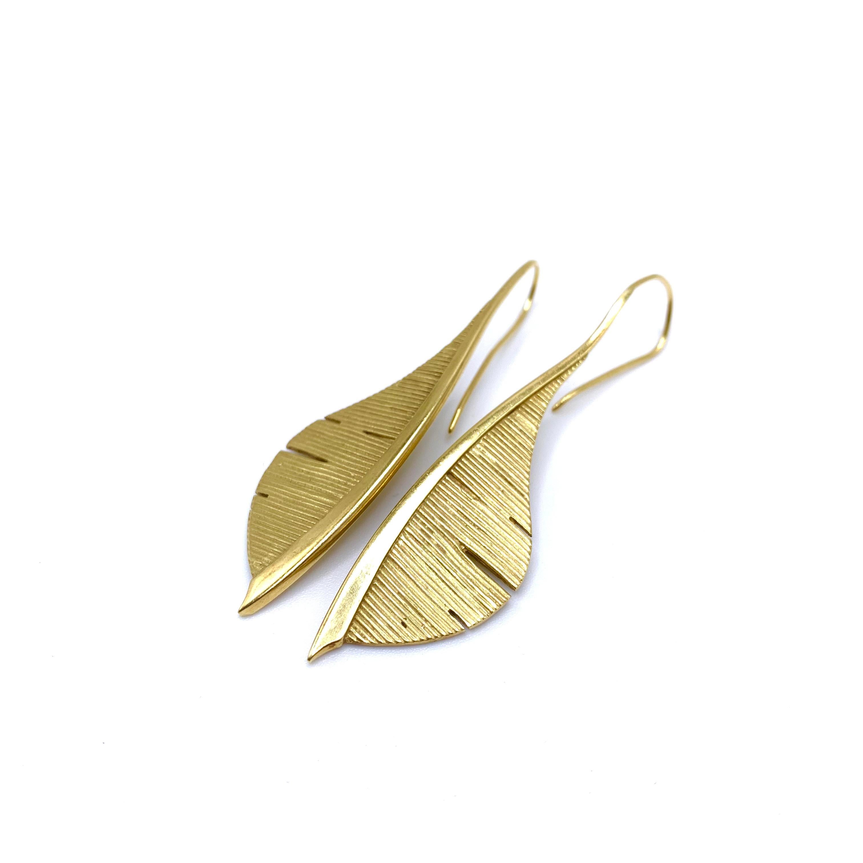 These feather earrings appear to be handmade and are crafted out of solid 18-karat yellow gold. They feature a shepherd's hook post that is .8 mm thick. The earrings themselves are 2.65