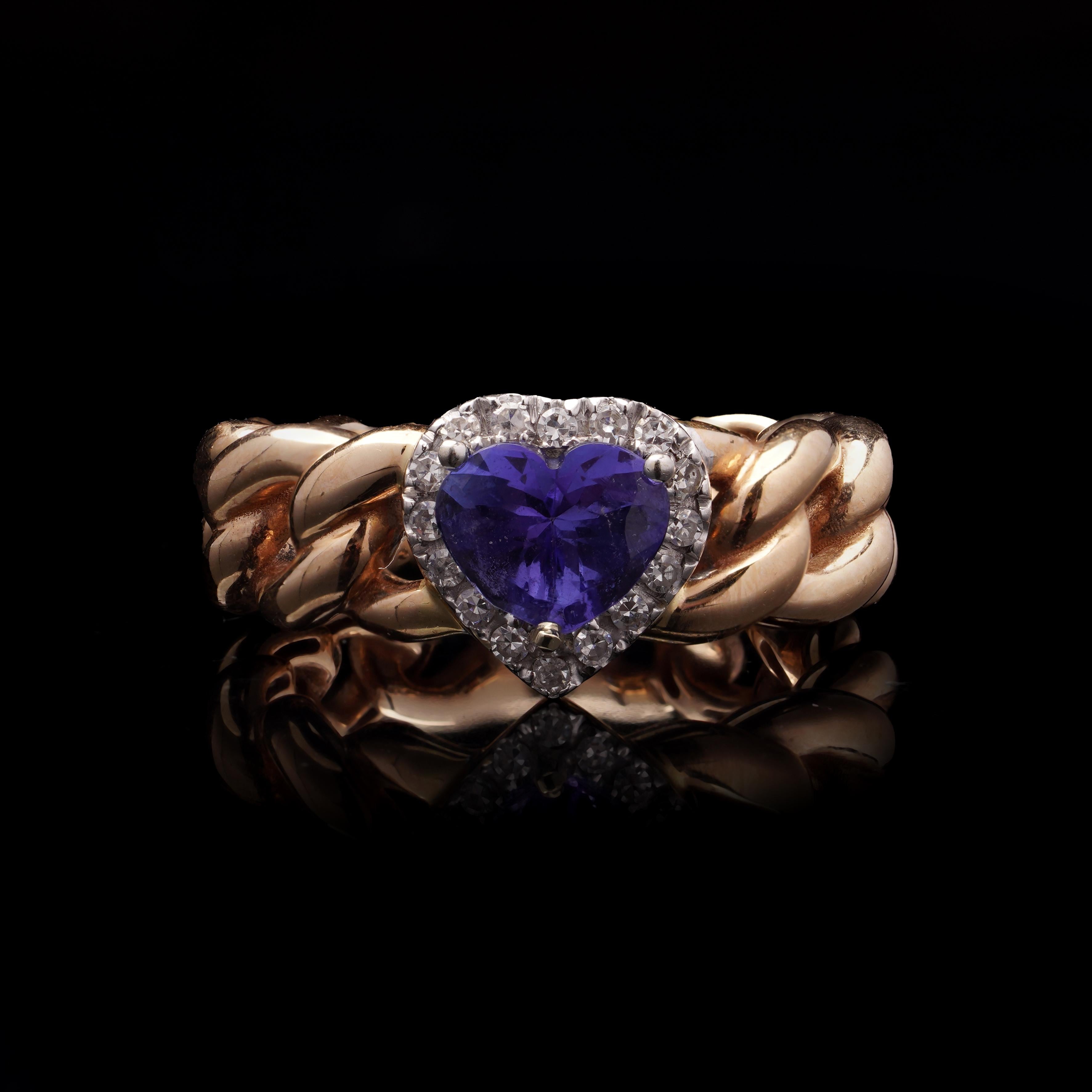 18kt Gold Heart-Shaped Tanzanite and Diamond Chain Link Ring

A modern 18kt gold ladies' ring featuring a distinctive heart-shaped tanzanite, framed by round brilliant-cut diamonds. The band is designed as a polished gold chain, giving the piece a