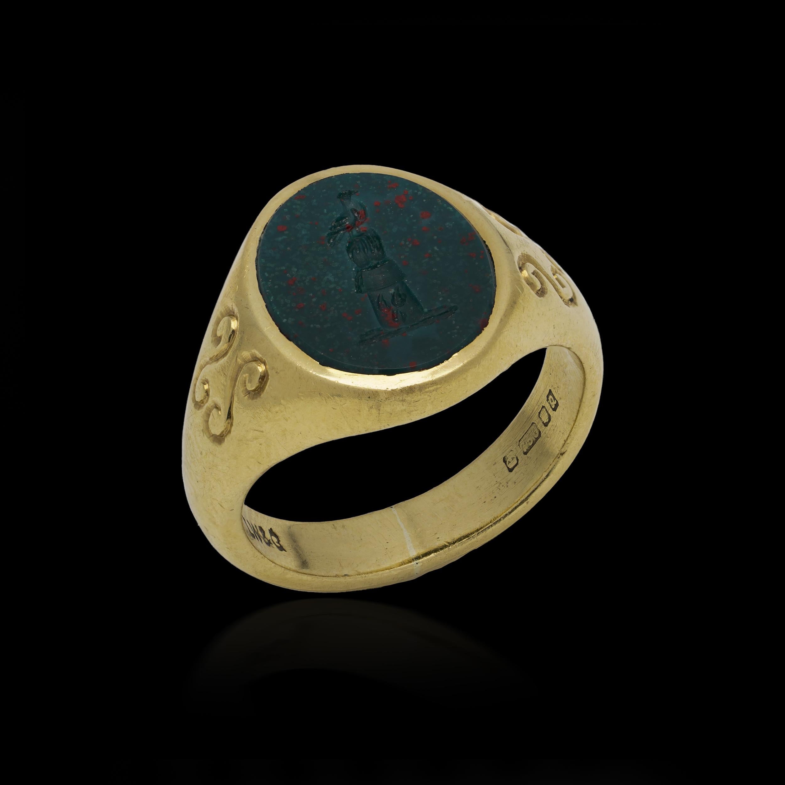 Anello con sigillo in oro giallo 18 carati, con incastonata un'incisione ovale in ematite finemente incisa con uno stemma araldico, che mostra una mano e un braccio emergenti che reggono  un uccello. 

La mano e l'uccello sono un classico simbolo di