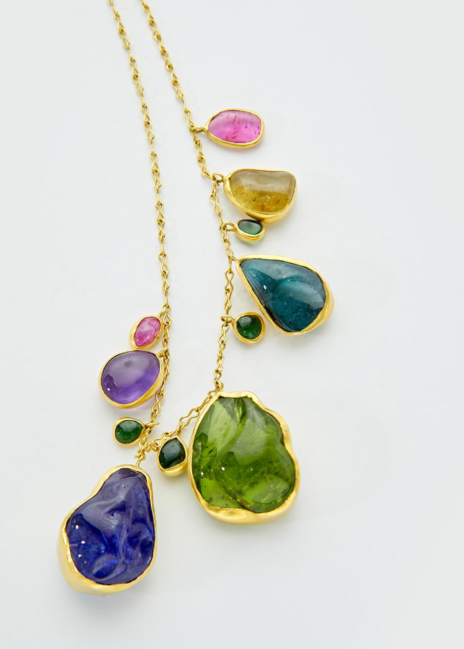 A gathering of a rainbow from large hand-cut gems beautifully tumbled large pebbles of African tanzanite, Burmese peridot and flashes of pink tourmaline set in a gold chain, make this a colourful and one-of-a-kind piece.
