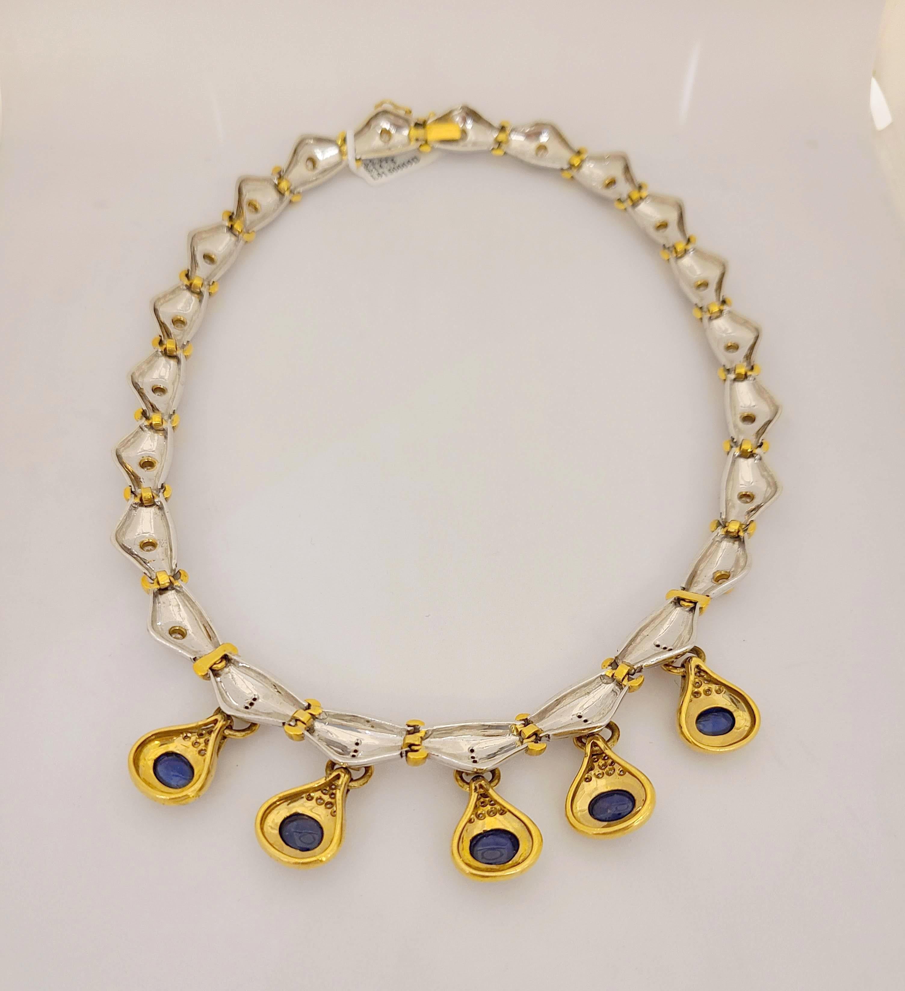 Diese schöne Halskette besteht aus 5 ovalen blauen Saphir-Cabochons, die jeweils in eine Fassung aus 18-karätigem Gelbgold eingefasst sind, die mit runden Brillanten akzentuiert ist. Die Saphire hängen an einer Halskette mit geriffelten Abschnitten