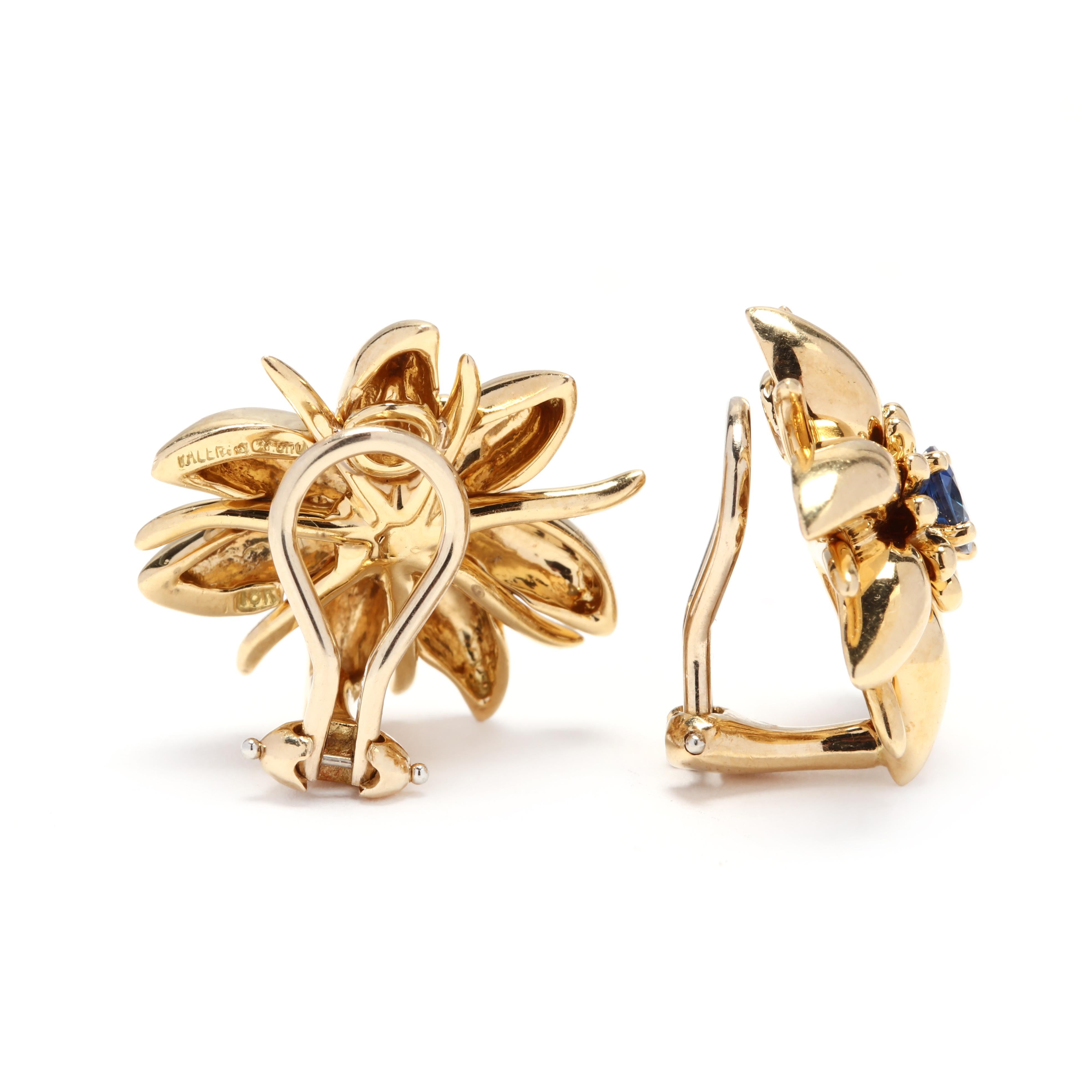 A pair of 18 karat yellow gold and sapphire flower earrings. These earrings feature a floral motif set with round cut sapphires and with omega backs.

Stones:
- sapphires, 2 stones
- round cut
- 5 mm
- approximately 1.40 total carat

Length: 7/8 in.