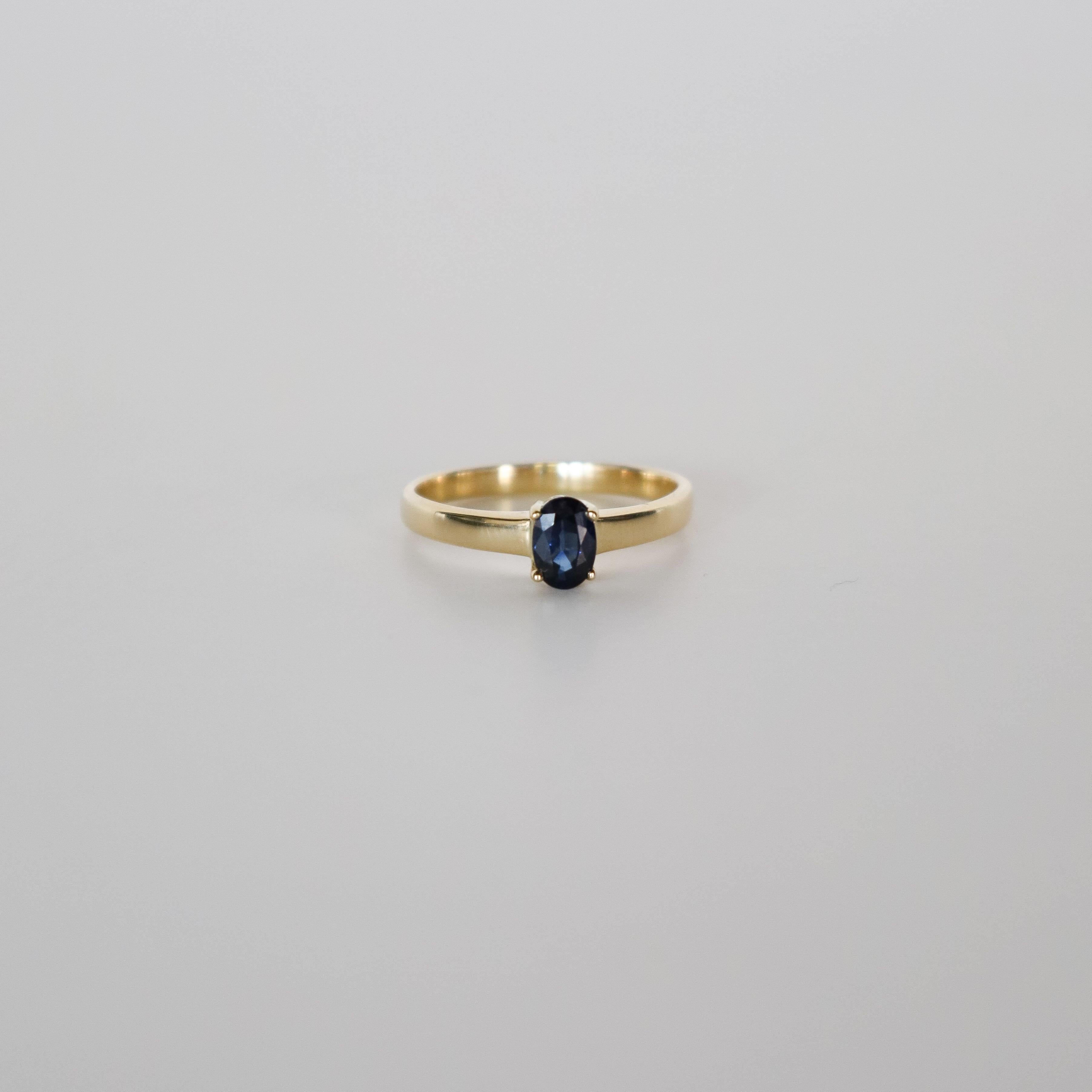 Add timeless elegance  with this 18k yellow gold solitaire ring, featuring a captivating oval dark blue sapphire. This beautifully crafted ring showcases the classic design, making it a standout piece for any occasion. Perfect for lovers of