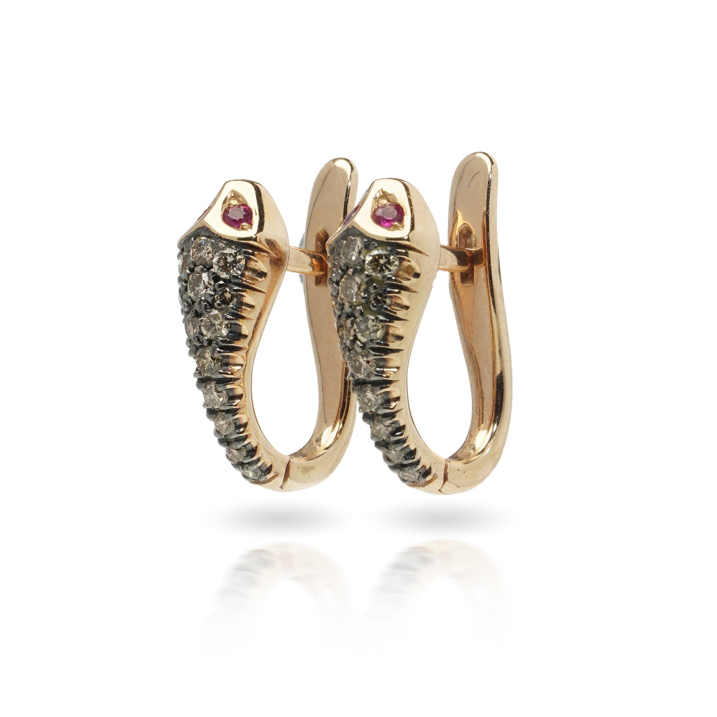 Coppia di orecchini a forma di serpente realizzati in oro rosa 18 carati, scolpiti in forme fluide e arricciate. Ogni orecchino è incastonato con diamanti rotondi a taglio brillante lungo il corpo e occhi di rubino. 

Questi serpenti avvolgono