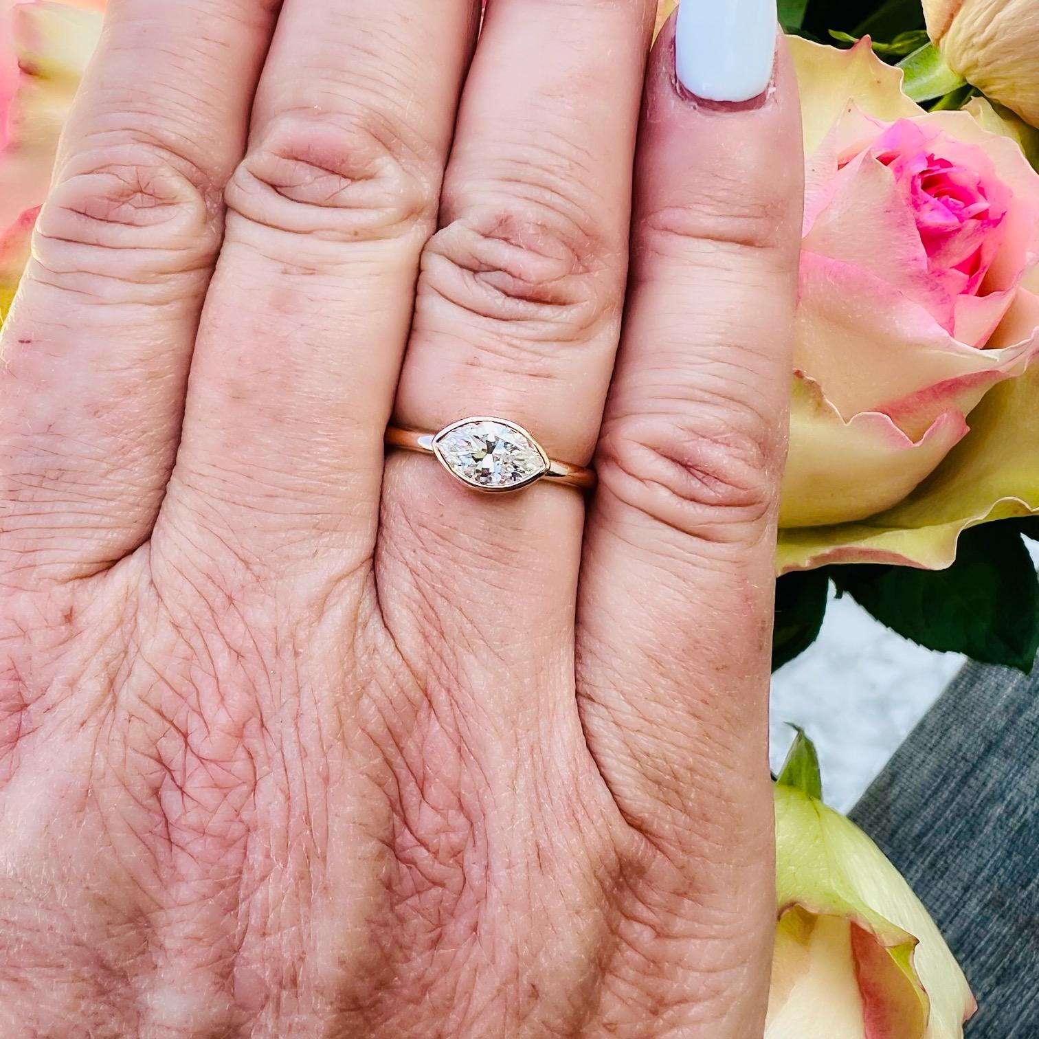 A classic cut diamond utilized in a uniquely modern way. This 18 karat rose gold ring features a solitaire natural marquise diamond weighing .80 carats horizontally bezel set with an open basket allowing maximum light to penetrate the stone