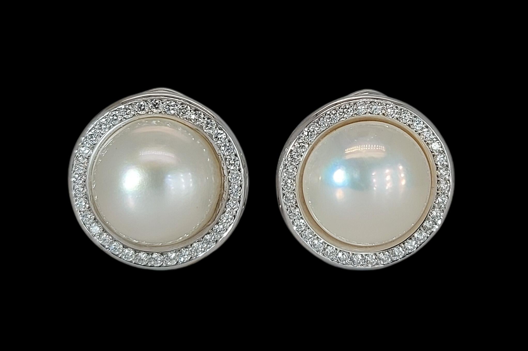 Superbes boucles d'oreilles à clip en perles de Mabe rondes entourées de diamants en 18 carats

Diamants : 64 diamants taille brillant 

Perle : Perle Mabe avec un diamètre de 13mm 

Matériau : or blanc 18kt

Mesures : Diamètre 18,3 mm x 21