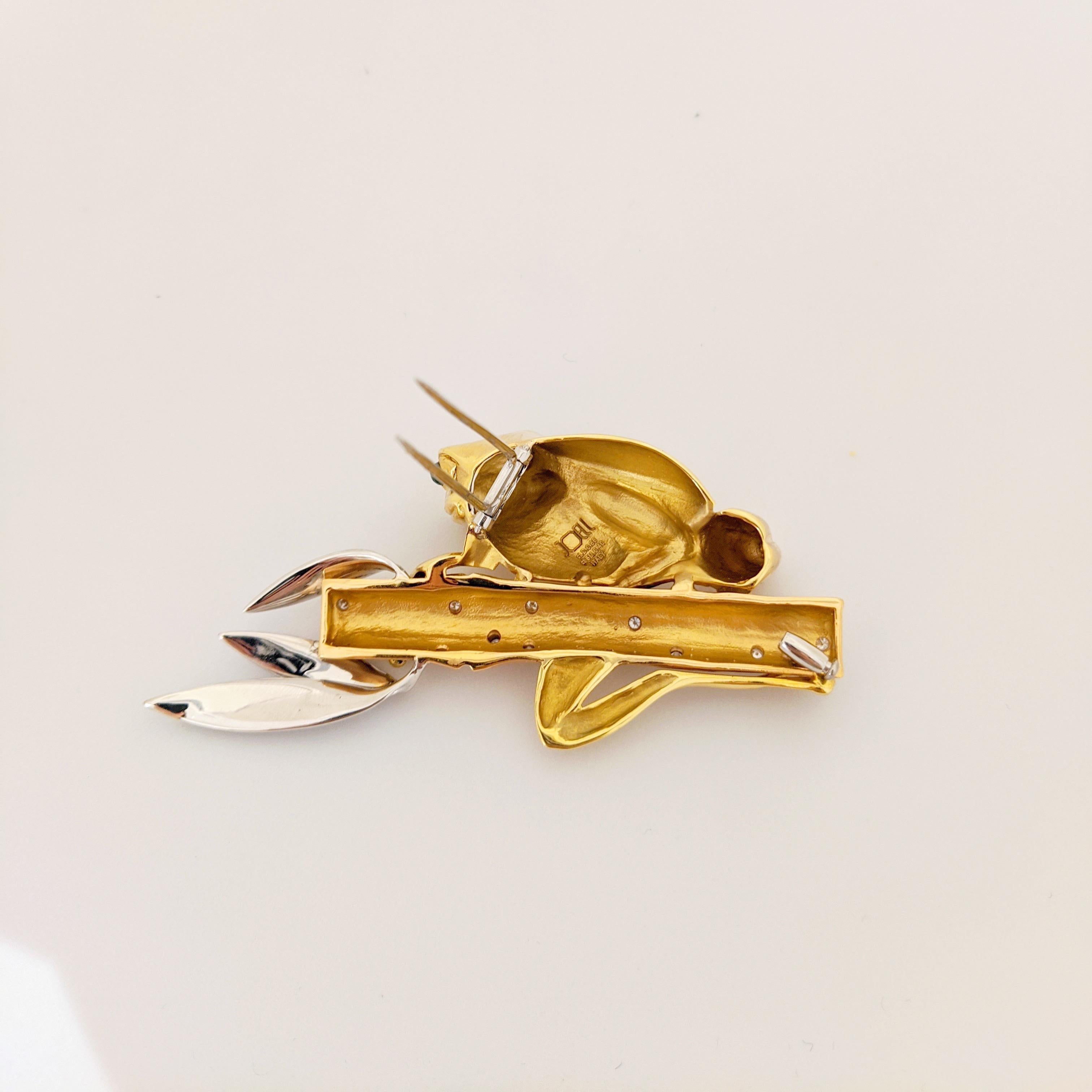 This lovely 18 karat gold brooch by Joell Prisma for Cellini Jewelers NYC, is designed with a hi-polished yellow gold frog with cabachon Emerald eyes. He is holding on to a Bamboo plant of rose gold, sprinkled with round brilliant Diamonds. The