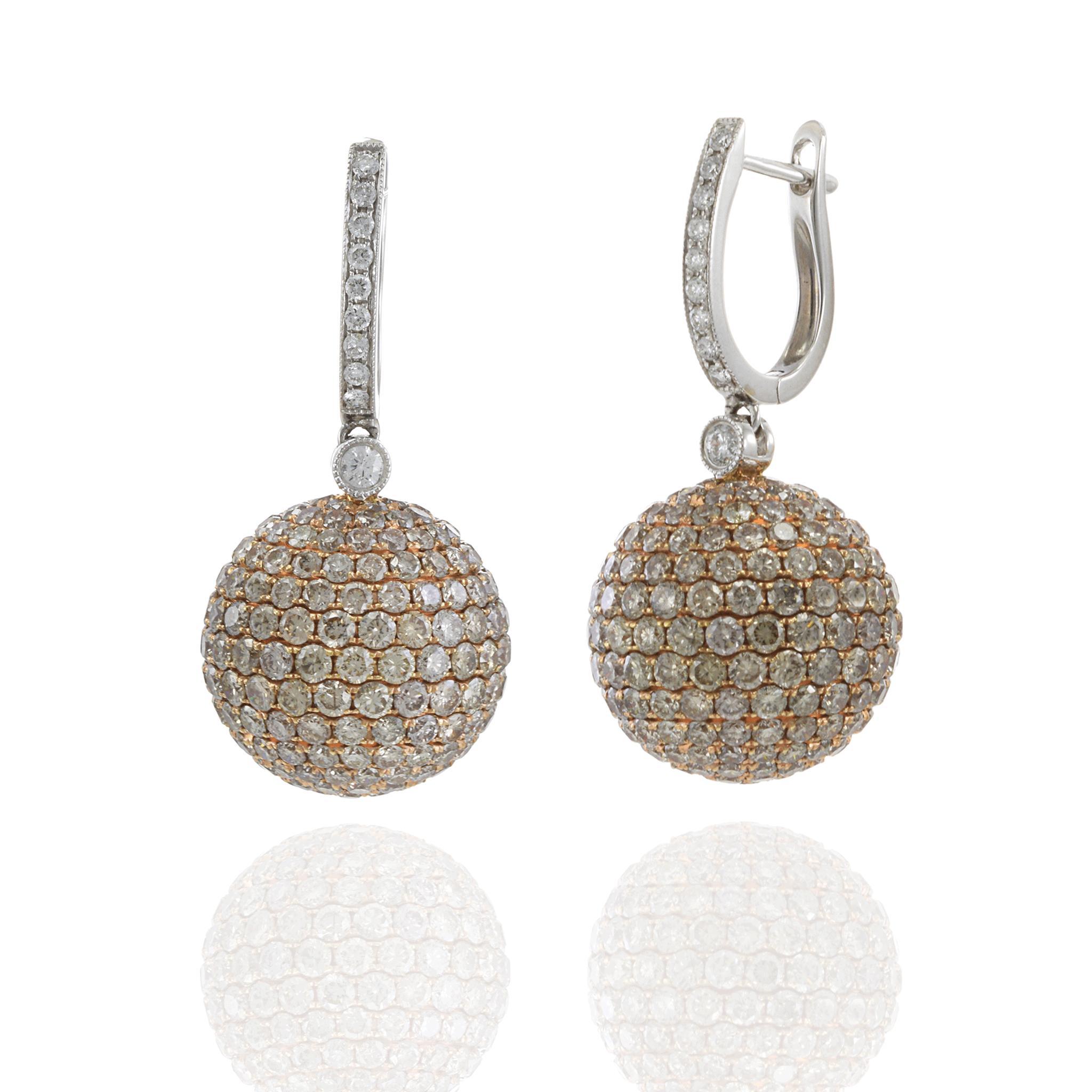 Ces boucles d'oreilles en forme de boule en diamant sont tout sauf subtiles. Conçue en or blanc et rose 18KT, chaque sphère est entièrement incrustée de diamants ronds et brillants de couleur champagne et blanche totalisant 12,06 carats. Les tons