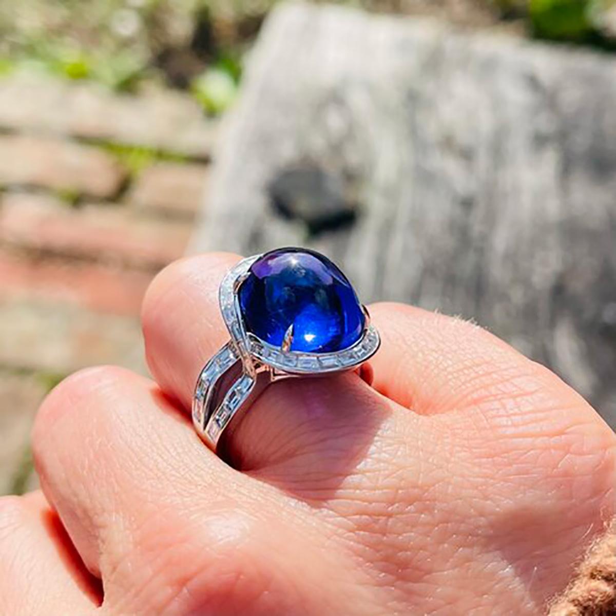 Exclusive 18kt white gold approximately 16 carats of oval tanzanite cabochon ring surrounded by baguette-cut diamonds.
Made in After 2000
Hallmarked for 750 platinum purity.  

Dimensions - 
Finger Size (UK) = L 1/2 (EU) = 53.5 (US) = 6.25
Weight: