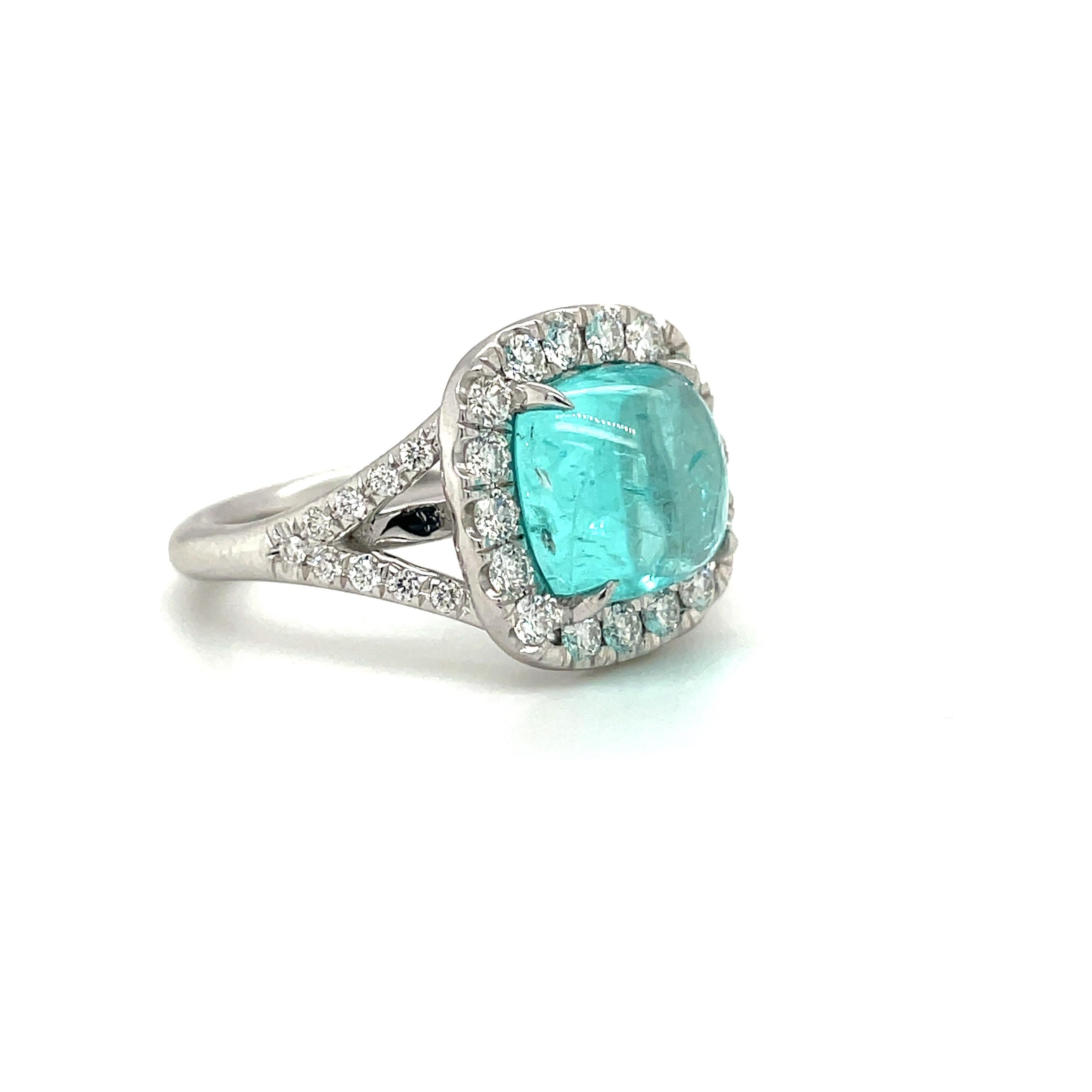 This 18 karat white gold ring centers a magnificent 4.07 carat cabochon paraiba tourmaline. The cushion shaped stone is surrounded by round brilliant diamonds. The shank of the ring is a split style set with round diamonds half way down the band.