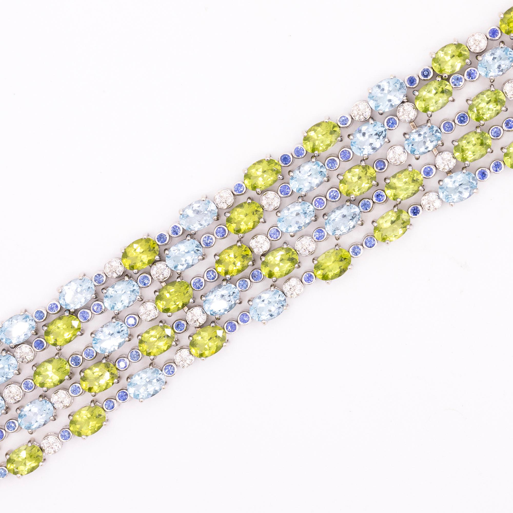 18kt white gold 5 strand bracelet, pave diamond set bar clasp with 30 round brilliant cut diamonds. Total weight is apprx. .60 carats. Each row is set with alternating oval peridots, blue topaz, interspersed with round blue sapphires set in round