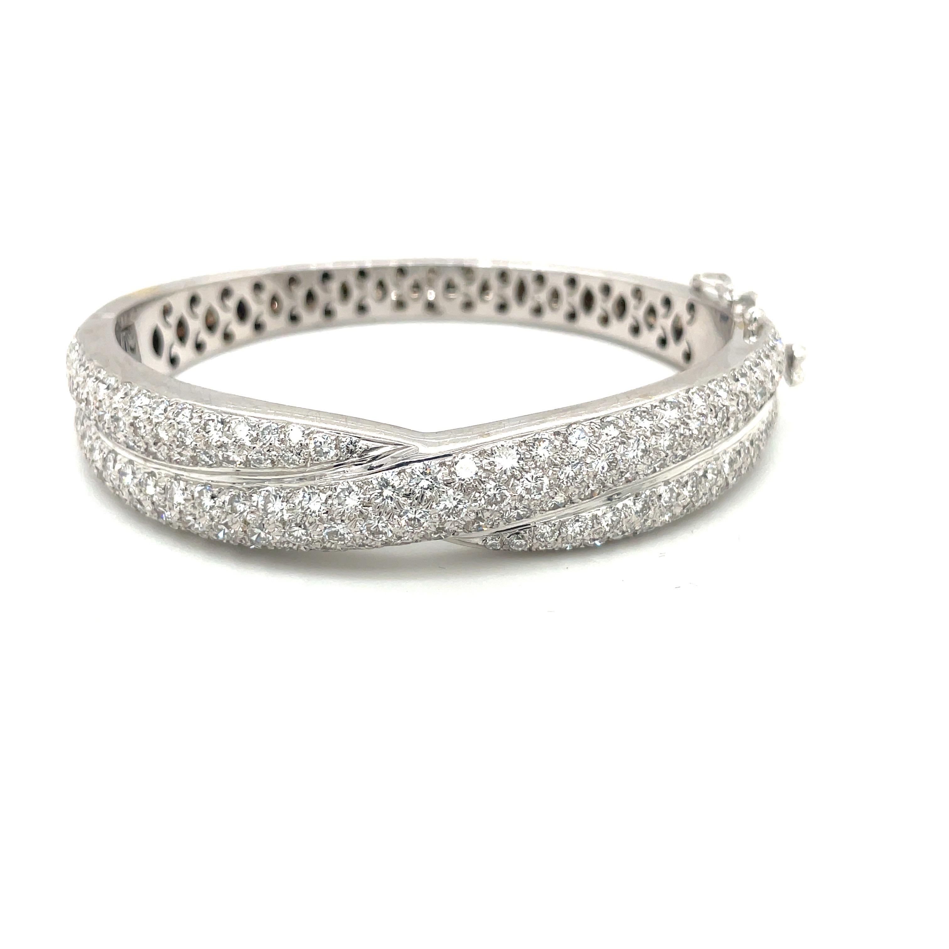 This 18 karat white gold and diamond bangle bracelet is set with 7.34 carats of round brilliant diamonds. The crossover design appears as 2 bangles. The oval shaped bracelet sits comfortably on the wrist.
Stamped 750 with the jewelers hallmark. The