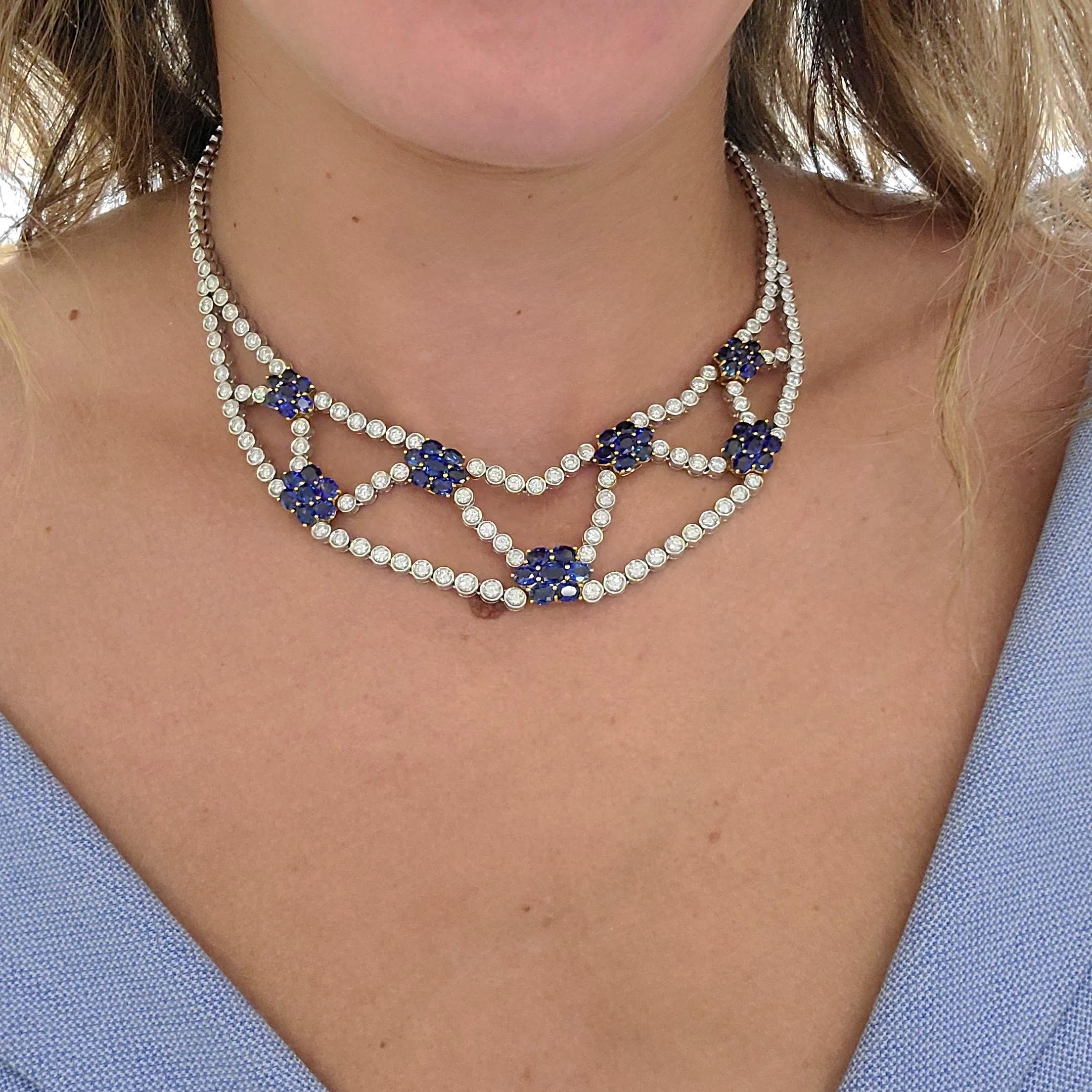 This necklace is designed with seven 18 karat yellow gold floral motifs , each set with seven oval Blue Sapphires. The necklace itself is bezel set round Brilliant Diamonds throughout, set in 18 karat white gold. The clasp at back is also another