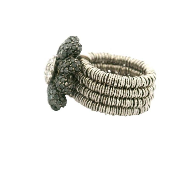 18kt white gold black diamond and white diamond spinning flower ring by Roberto Demeglio.  This expandable ring is a size 6.5 and expands comfortably to a size 9.  The shank of the ring is composed of white gold rings over three spring steel cable