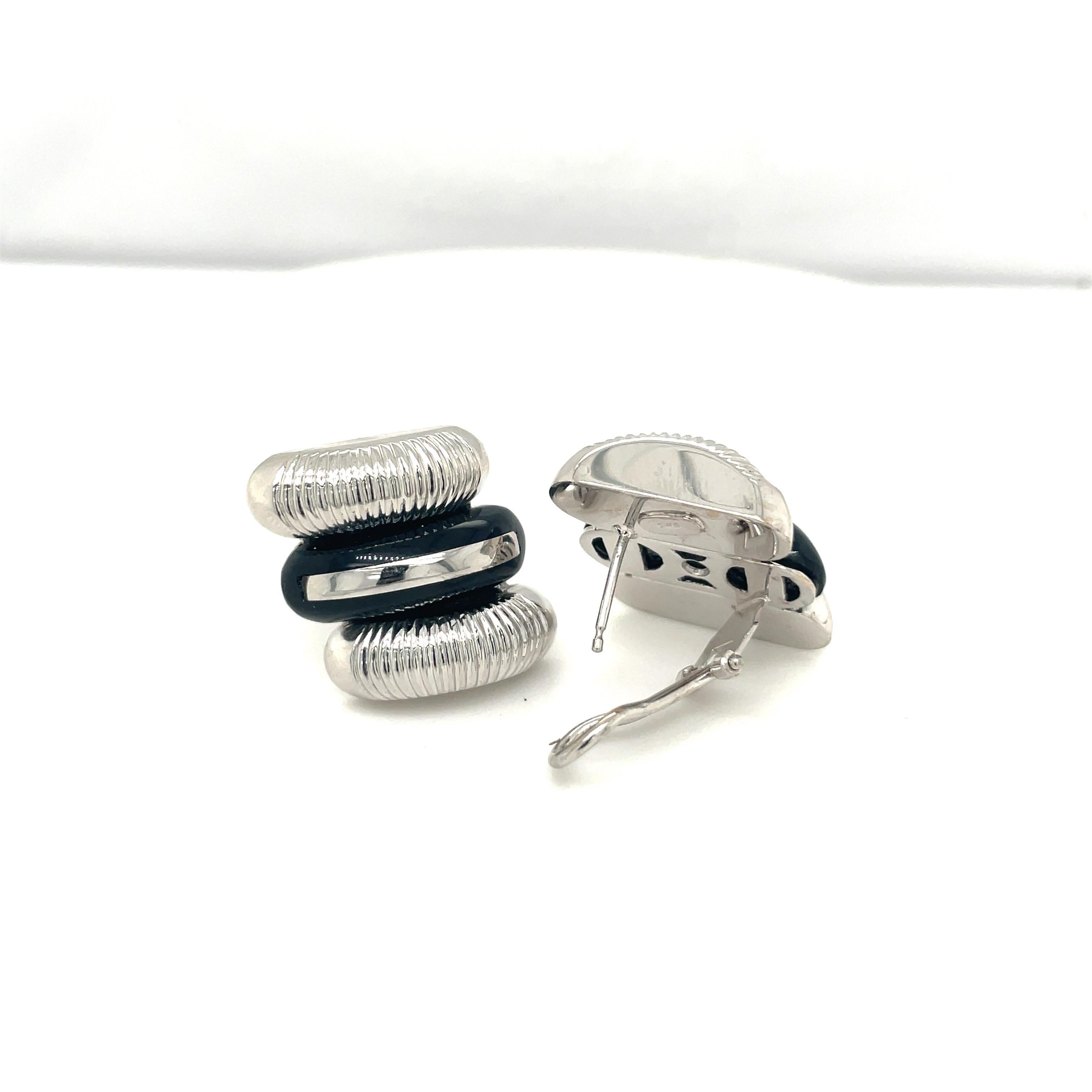 A very classic pair of 18 karat white gold earrings. The earrings are designed with 2 ribbed sections of on either end, and a black onyx section in the center. The earrings are pierced and can be adjusted to clip on. They measure approximately