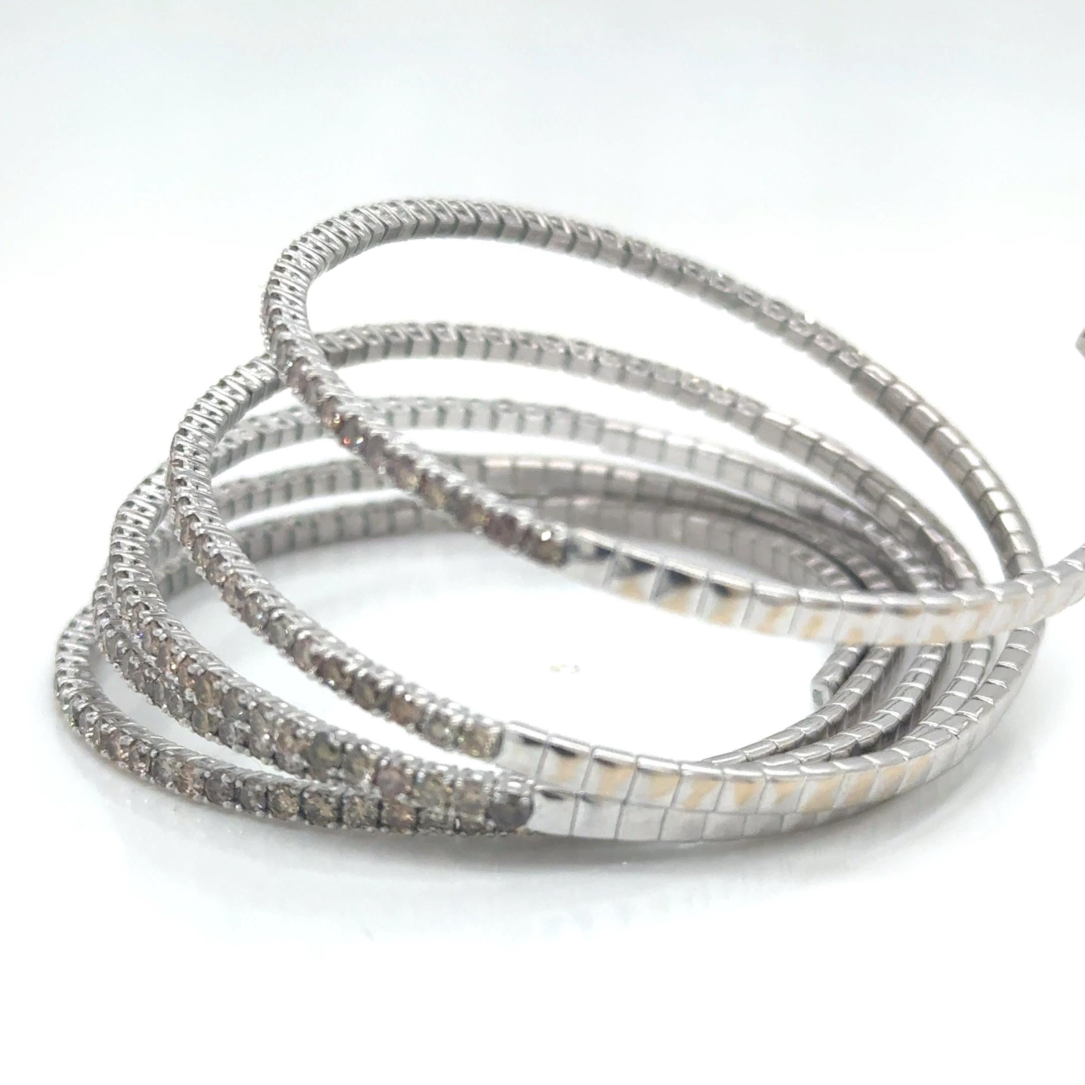 An exquisite embodiment of sophistication and modern allure, this wrap-around bangle bracelet is masterfully crafted in 18 karat white gold, offering a luminous contrast to the warm, enchanting tones of champagne diamonds. With approximately 7.04