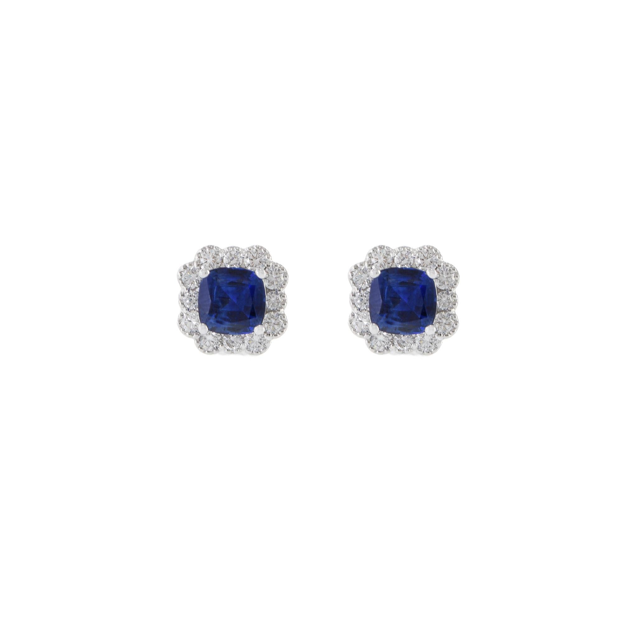 Ces boucles d'oreilles en or blanc 18KT présentent un design époustouflant, avec un saphir bleu central de 1,55CT-TW taillé en coussin, entouré d'un halo de 0,47CT-TW G-VS diamants ronds taillés. La juxtaposition du saphir bleu profond et des
