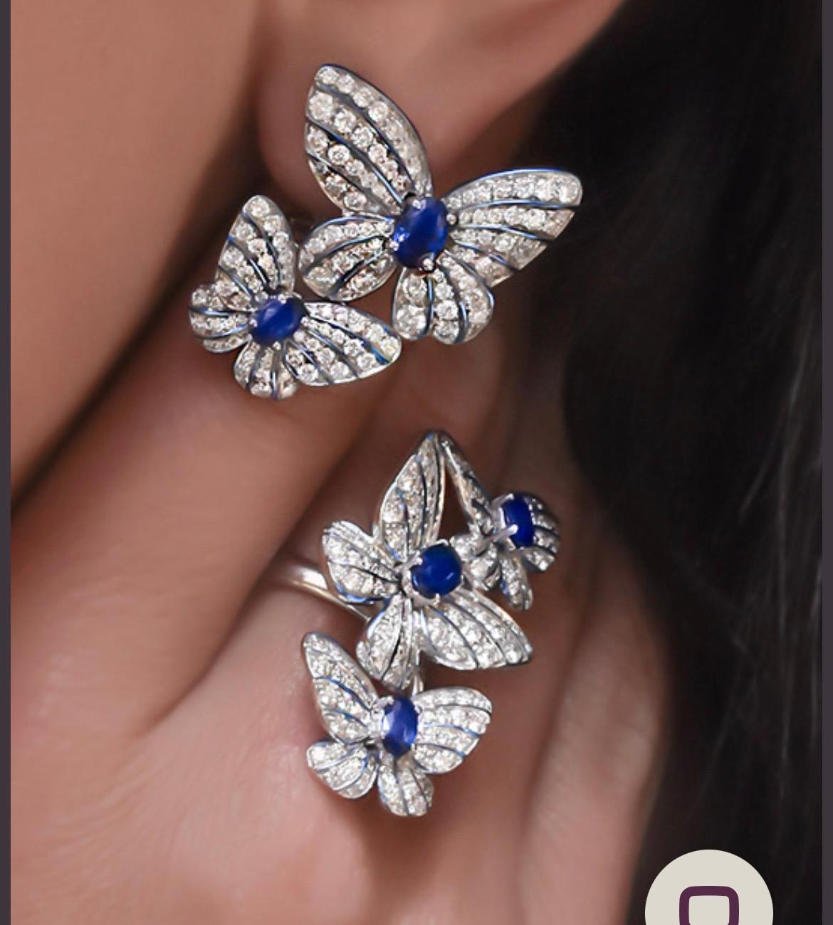 Magnificent 18 karat white gold ring designed with 3 pavé  diamond butterflies. 
Each butterfly centers an oval blue sapphire. The delicacy and vibrancy of the butterfly is further enhanced with hand painted iridescent blue enamel.
Total Diamond