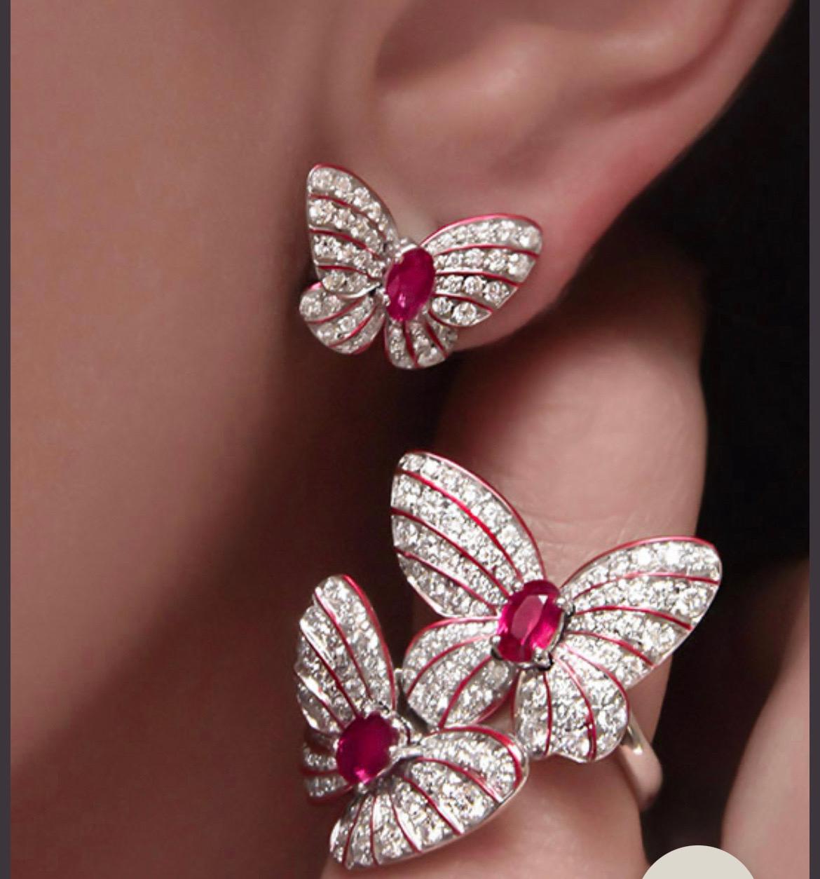 Magnificent 18 karat white gold ring designed with 2 pavé  diamond butterflies. 
Each butterfly centers an oval ruby. The delicacy and vibrancy of the butterfly is further enhanced with hand painted iridescent red enamel.
Total Diamond weight =1.70