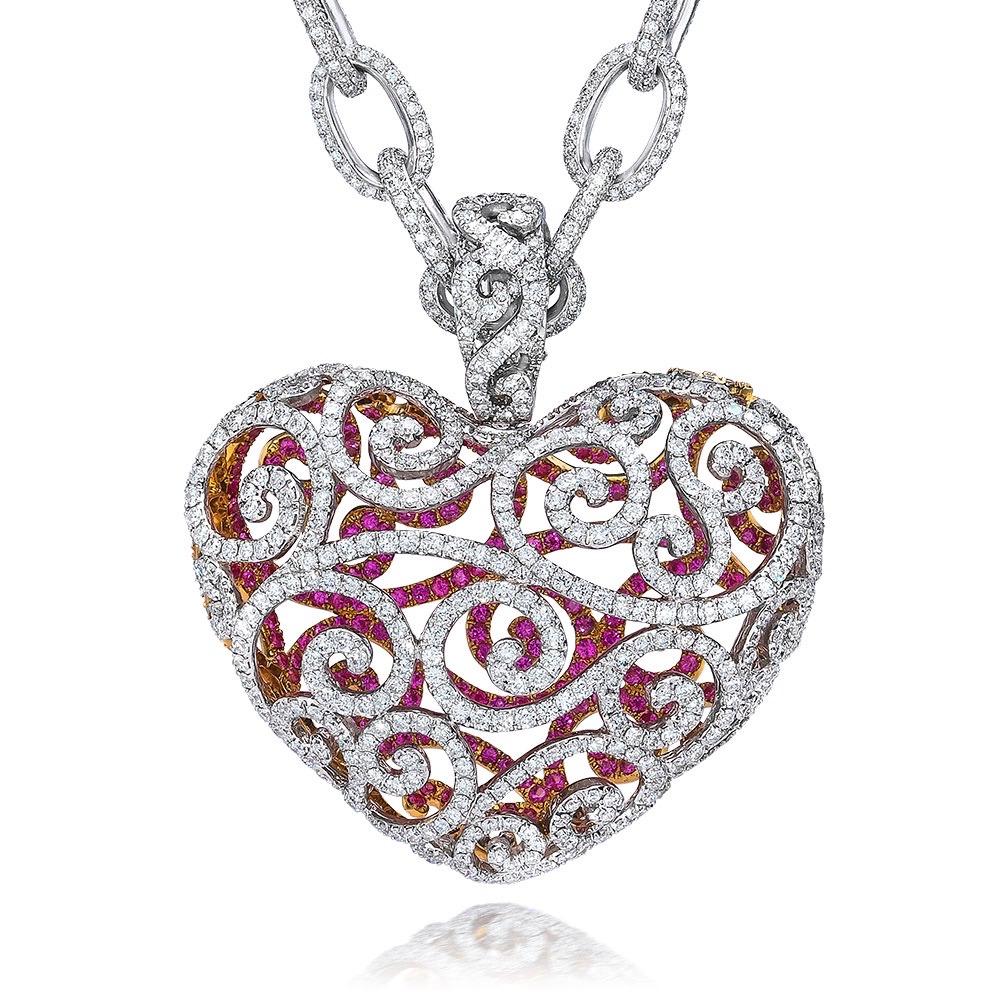 Designed with a Princess in mind, this 18 karat white gold Diamond heart pendant shows meticulous craftsmanship. The front of the puffed heart is pave set with round Diamonds in an open worked scroll pattern. The open work allows you to see inside