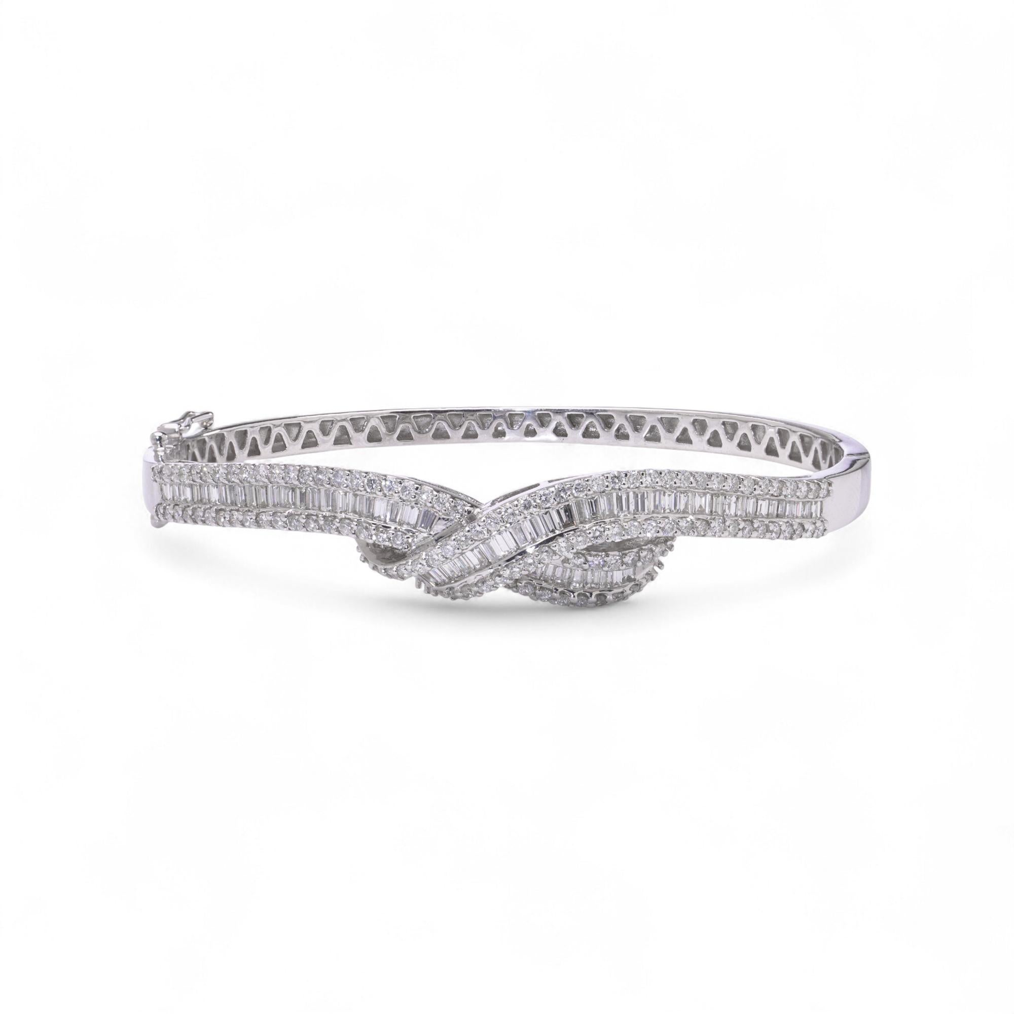 Élégant bracelet en or blanc 18kt orné de diamants et conçu avec un motif croisé torsadé. La face avant est sertie de diamants de taille baguette et de diamants ronds de taille brillant disposés en rangs alternés, créant un jeu de lumière et de