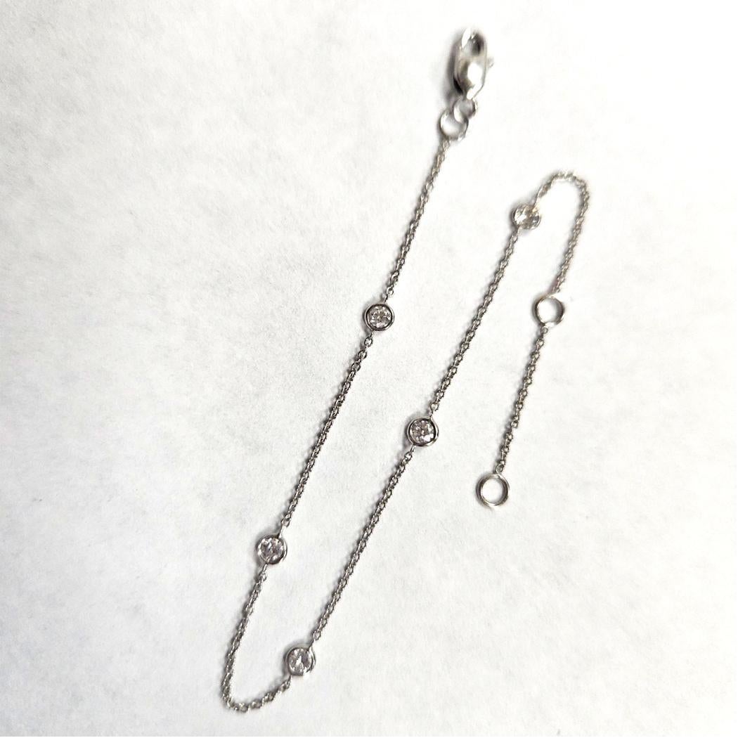 Cet élégant bracelet en or blanc 18 ct à diamants by-the-yard présente cinq diamants ronds de taille brillant, chacun solidement serti et uniformément espacé le long d'une délicate chaîne en câble. Les diamants ont un poids total combiné de 0,20