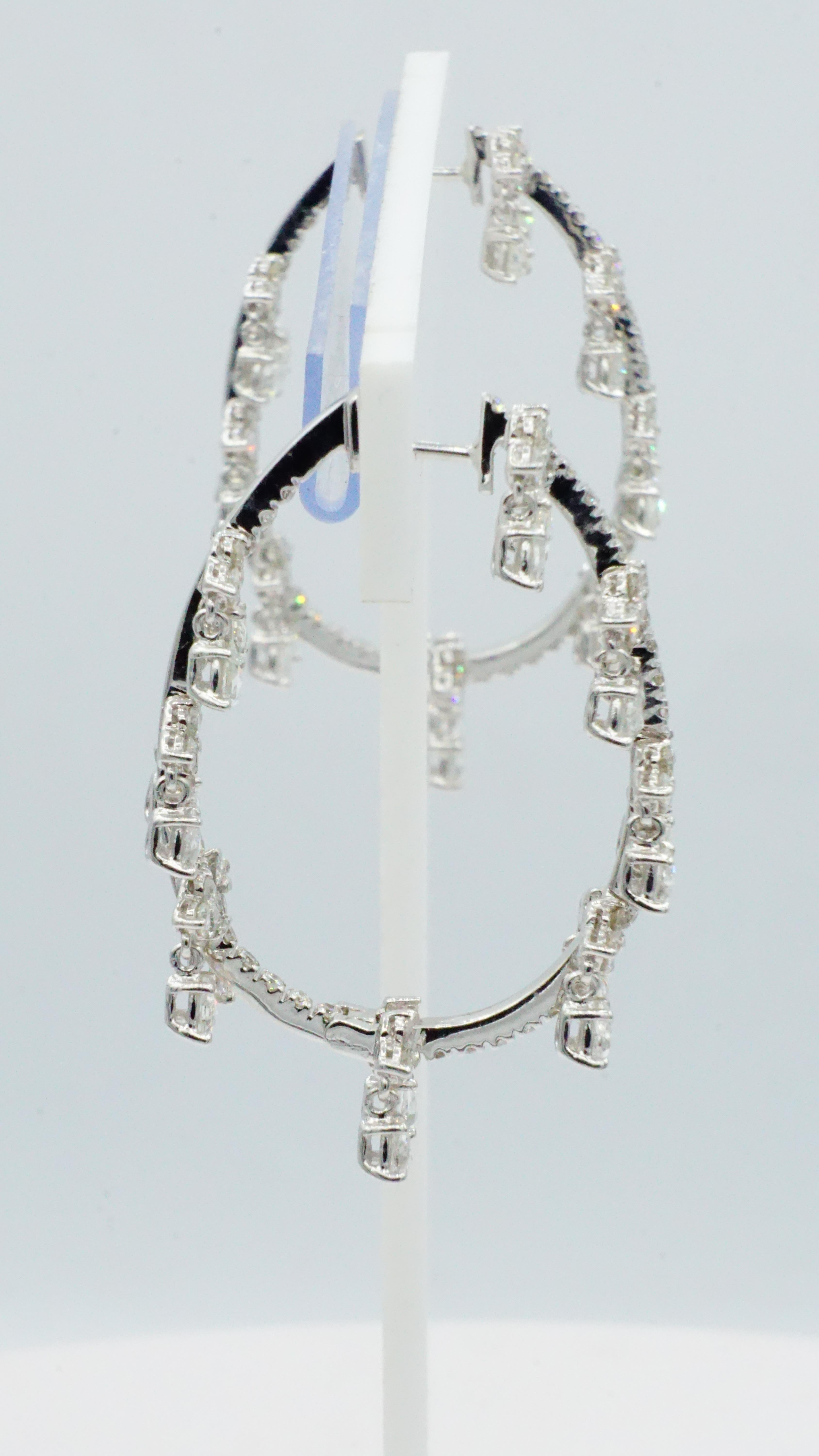 Beautifully-crafted 18kt white gold, hinged oval dangle-style, inside-out diamond hoop earrings. Each earring is 1.5 inches long and 1 inch wide. These earrings are in very nice like-new condition and timeless addition to any jewelry collection. 