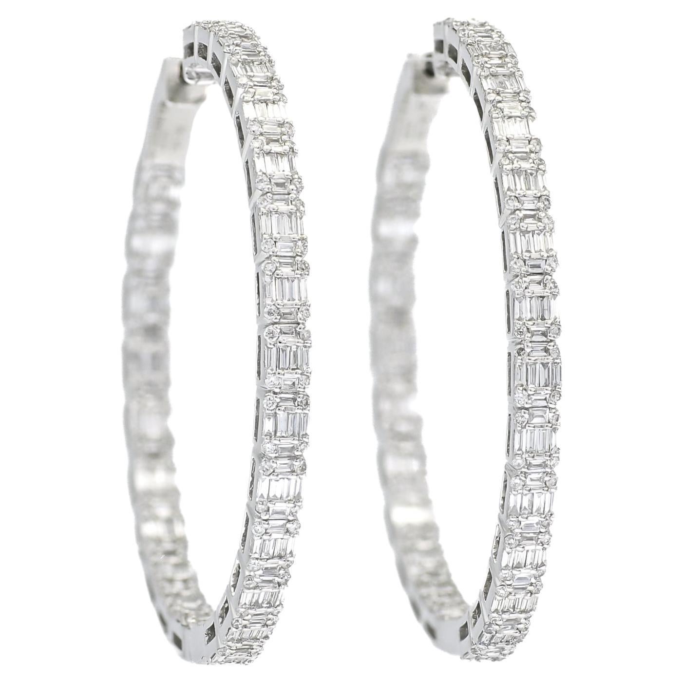 The cluster of baguette and round diamonds in these 18KT White Gold Illusion Hoop Earrings is an exquisite display of craftsmanship and artistry. This combination embodies the elegance and sophistication of classic jewelry design while introducing a