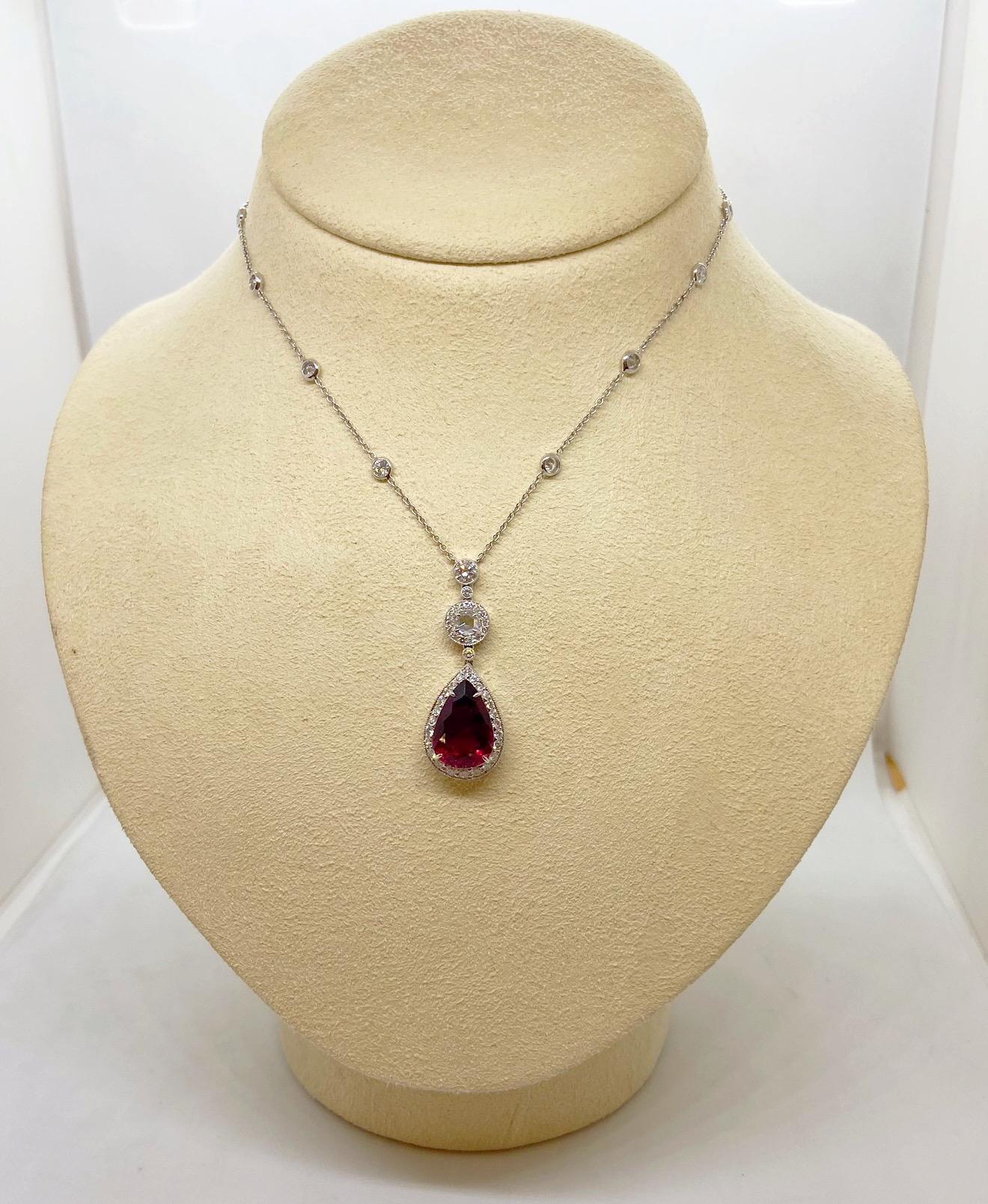 This 18 karat white gold pendant is designed with a pear shaped Rubelite drop. The center stone is joined with a rose cut Diamond, both are set in Diamond bezels. The drop pendant hangs from a white gold chain set with 10 bezel set round brilliant