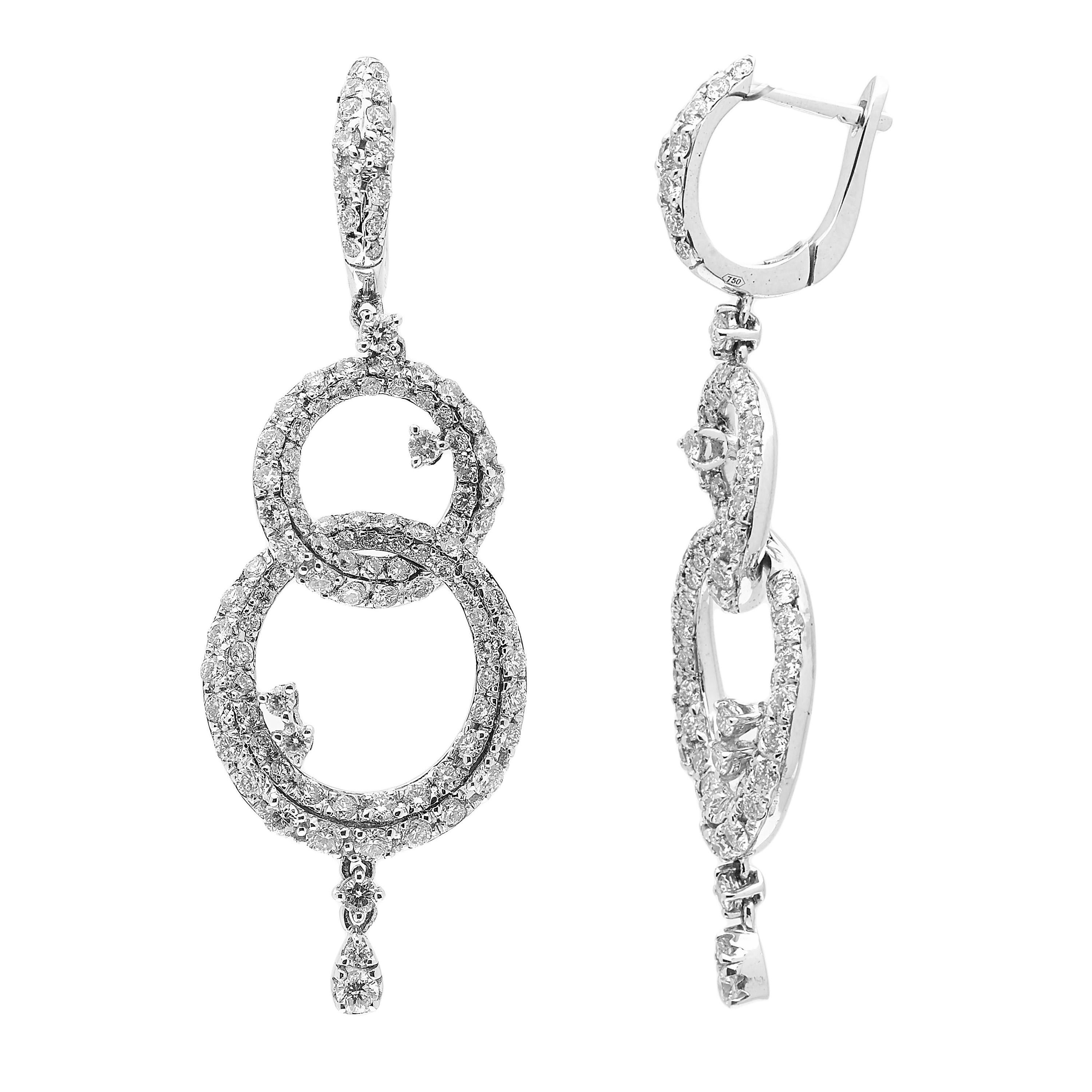 These unique drop earrings fashioned in 18kt white gold feature double interlocking hoops covered in a bright white diamond pavé totalling up to 3.59ct. A few floating stones on the inside of the hoops add to that extra special unique feel. 
