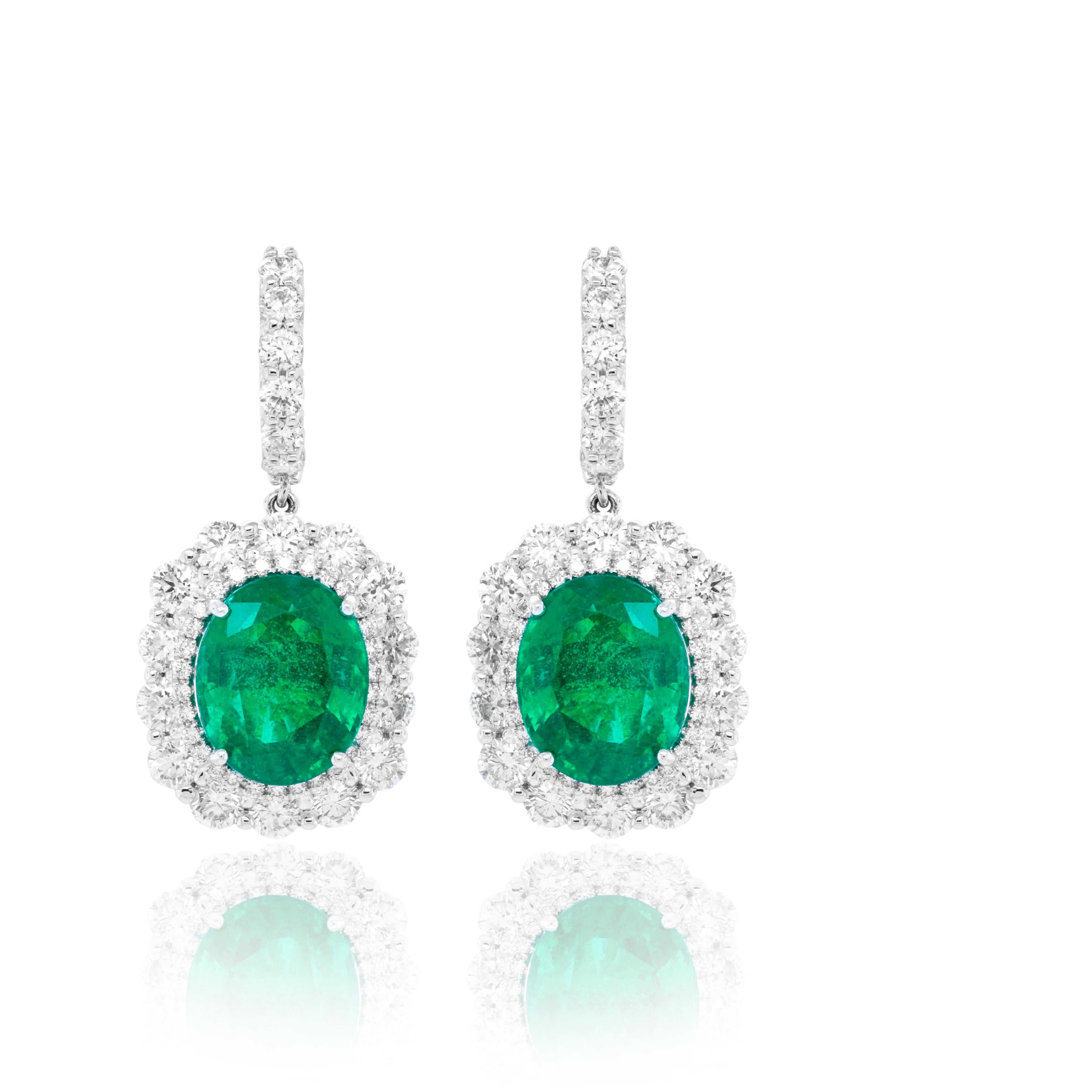 18kt white gold emerald & diamond earrings features 12.98 carats of gia certified oval green emeralds with 6.00 carats of round white diamonds set all the way around
