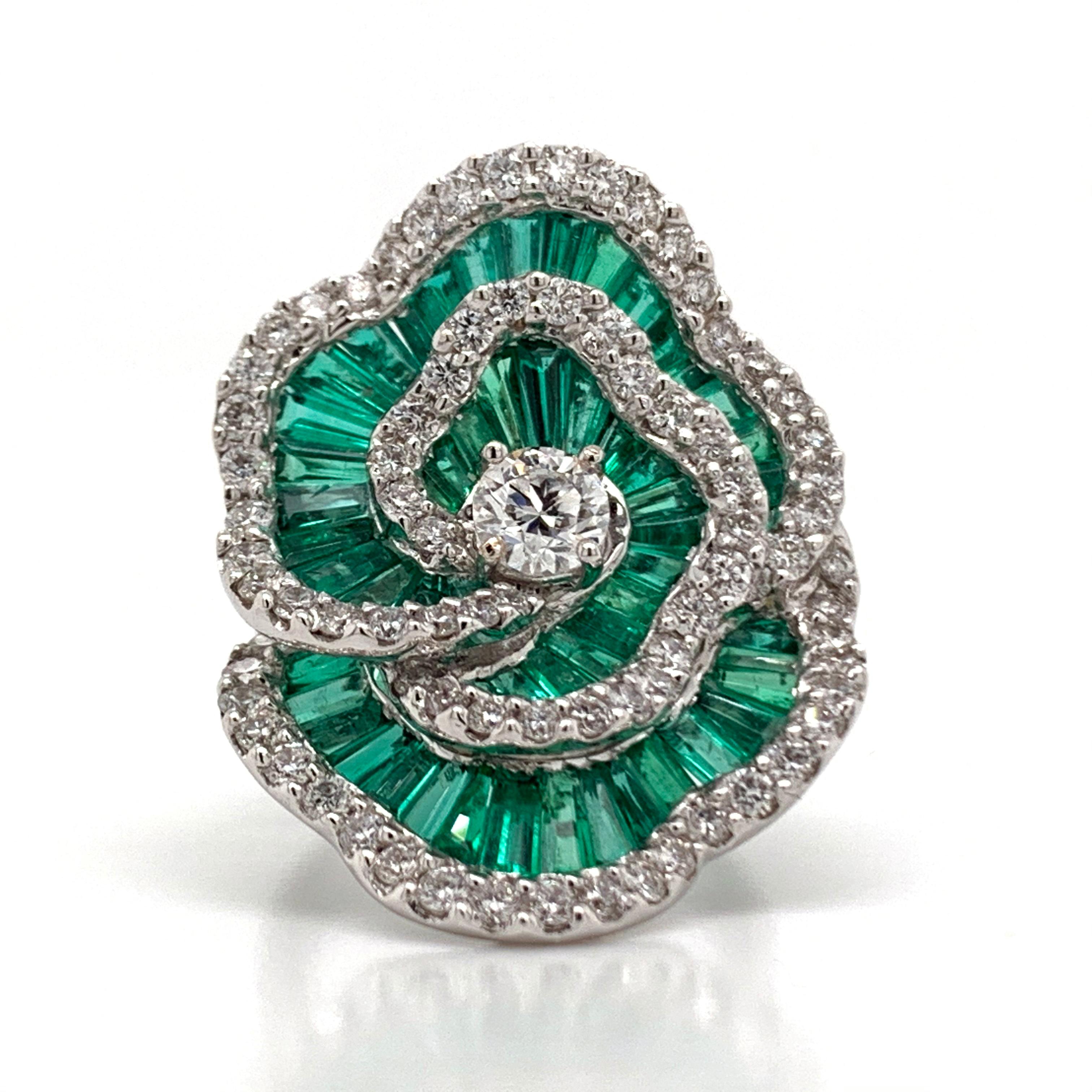 A beautiful, emerald and diamond flower ring in a US ring size 6.75 . This beautiful, gold ring  weighs 15.1 grams. Crafted, in a polished white gold the ring is includes an array of beautifully shaped emeralds showered on top by gorgeous sparkling