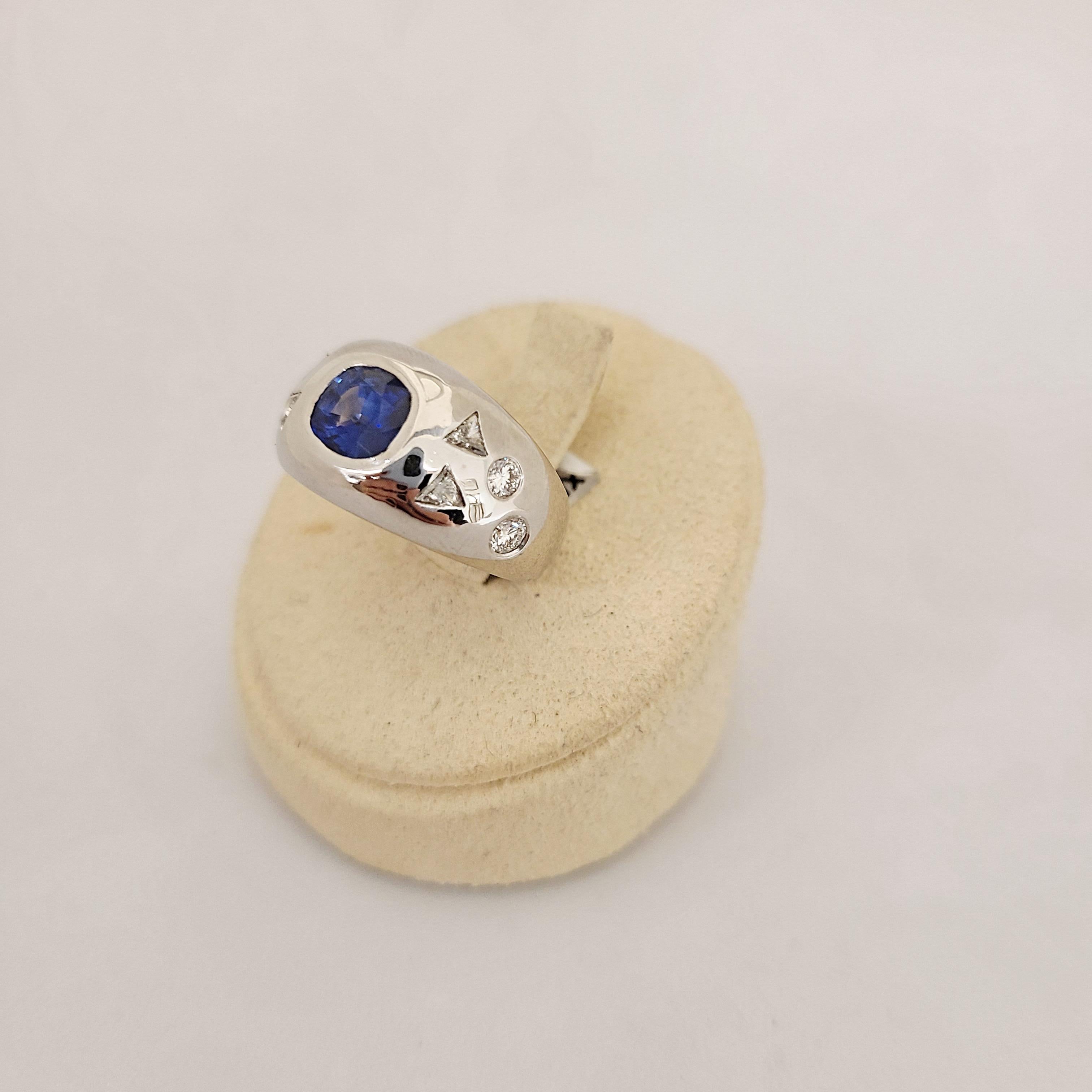 Made with superior quality, this show stopping white gold gypsy ring makes a fabulous right hand ring or unique wedding band. The cushion cut blue sapphire ring is 1.81cts and is flanked by 0.60 cts of round and trillion cut diamonds. Stones are