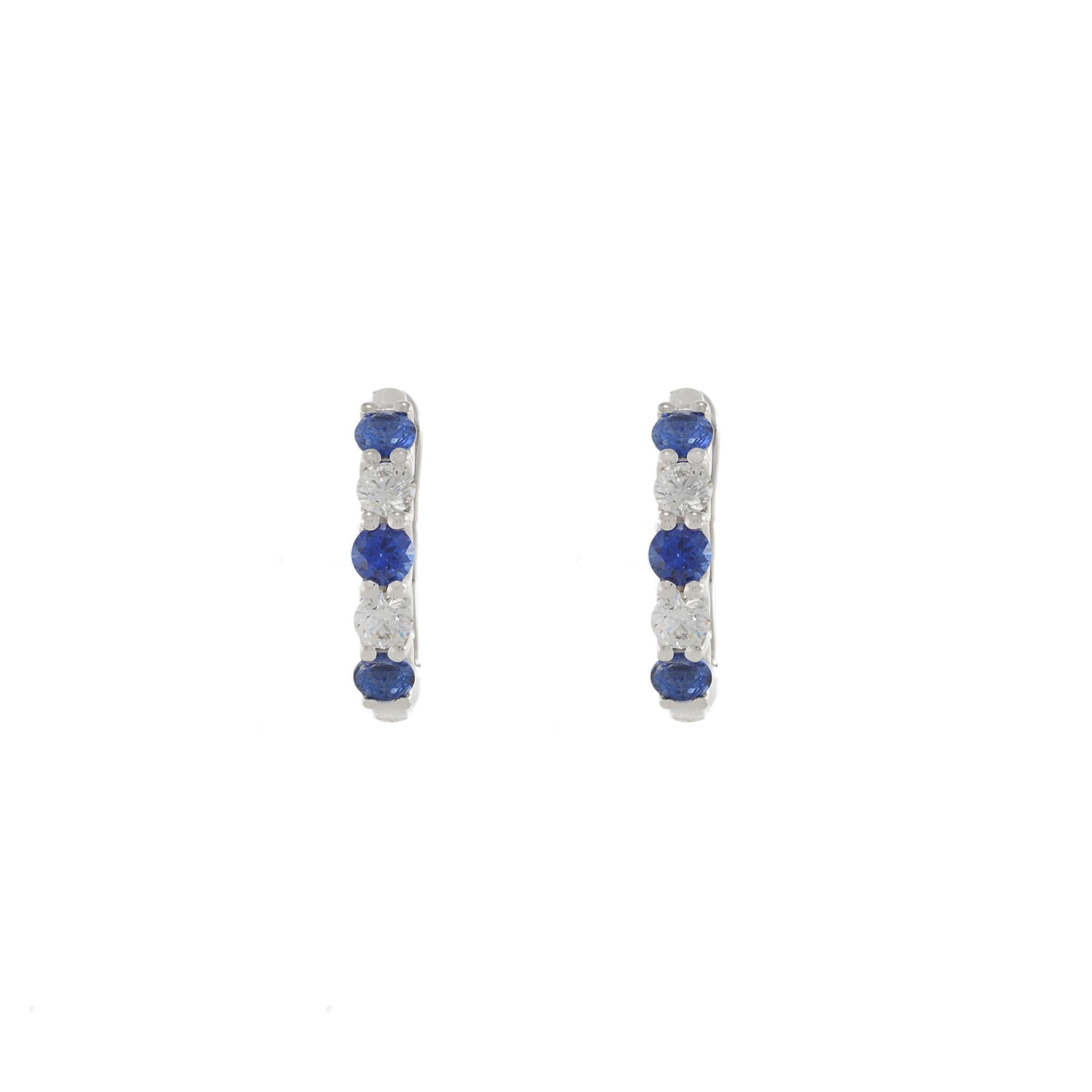 Orecchini Huggie in oro bianco 18KT con diamanti e zaffiri taglio rotondo alternati. Questi eleganti orecchini presentano zaffiri blu per un peso totale di 0,72 carati e diamanti taglio rotondo G-VS per un peso totale di 0,36 carati. Il motivo