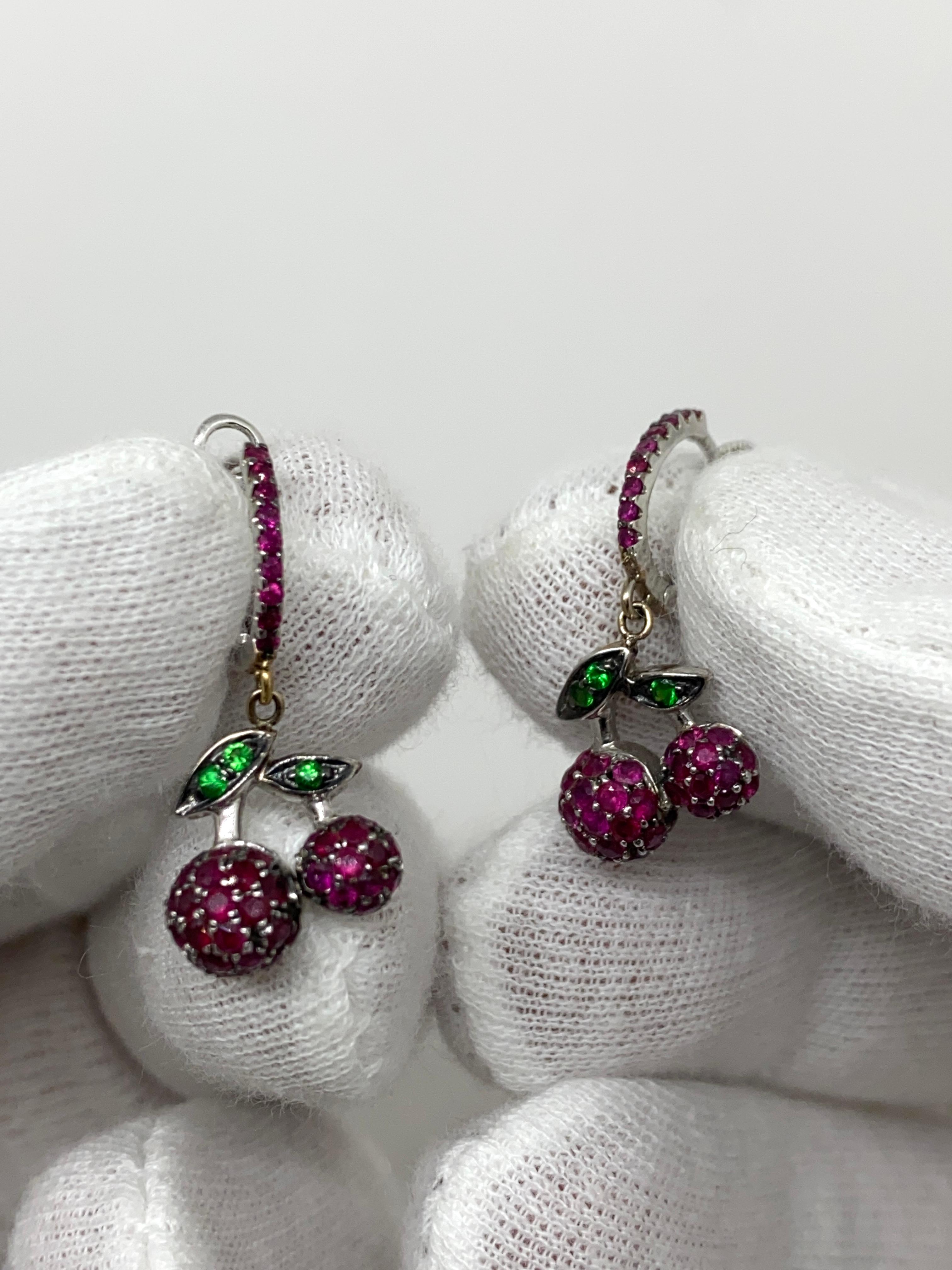 Drop earrings made of 18kt burnished white gold with natural brilliant-cut rubies and green tsavorite.

Welcome to our jewelry collection, where every piece tells a story of timeless elegance and unparalleled craftsmanship. As a family-run business