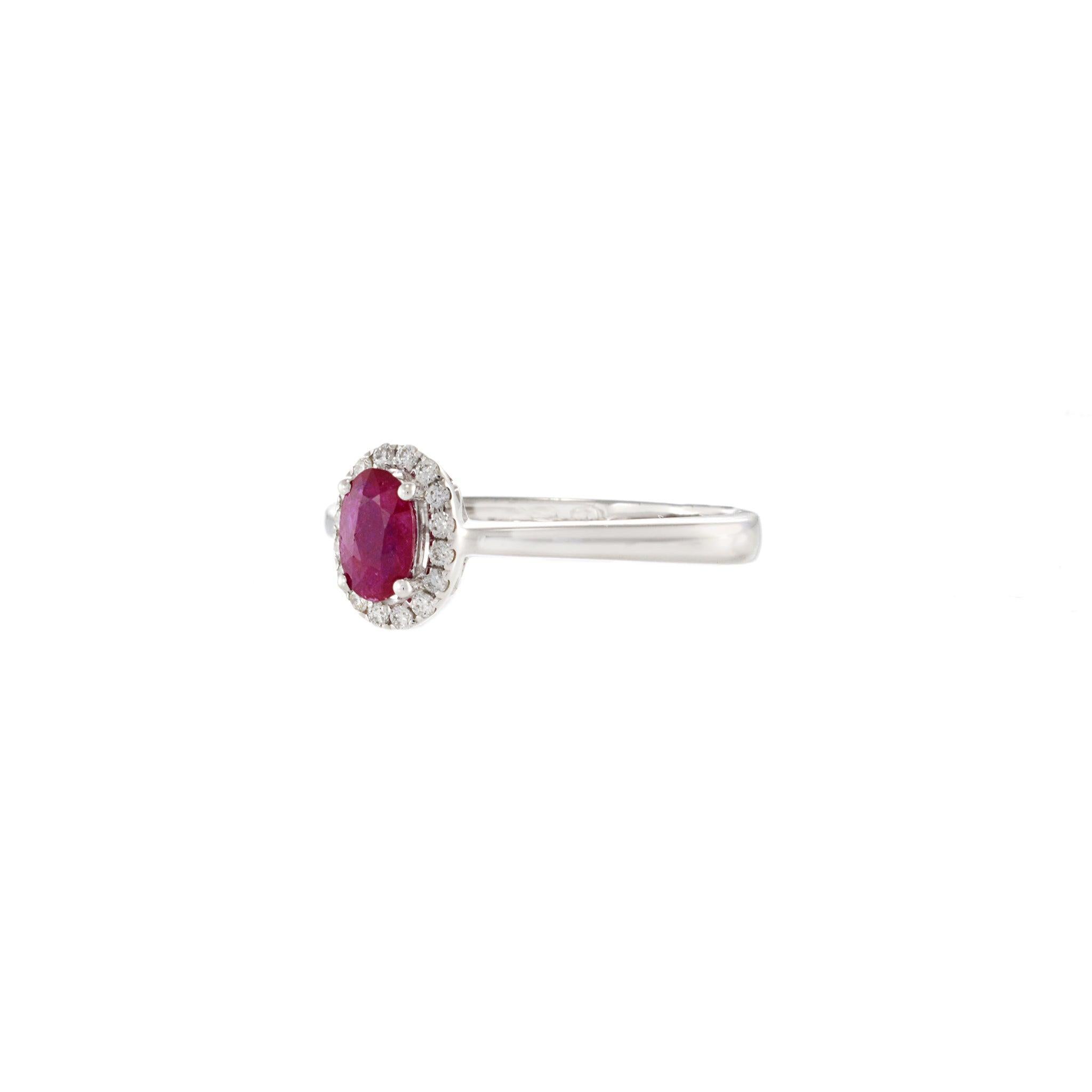 Delicato e raffinato, questo anello in oro bianco 18KT presenta un vibrante rubino ovale da 0,43 carati incorniciato da un'aureola di diamanti tondi brillanti per un totale di 0,11 carati. La ricca tonalità rossa del rubino è contrastata con