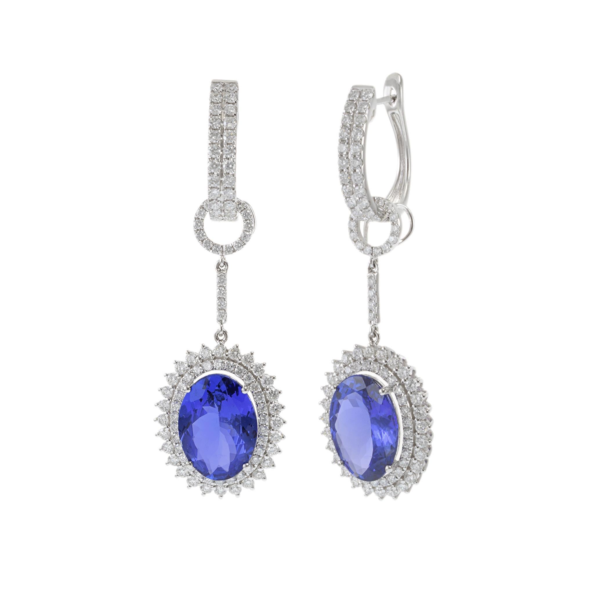 Ces superbes boucles d'oreilles pendantes sont réalisées en or blanc 18KT et mettent en valeur deux tanzanites de taille ovale d'une valeur totale d'environ 9,77 carats. Chaque tanzanite d'un bleu vif est entourée d'un halo étincelant de diamants de