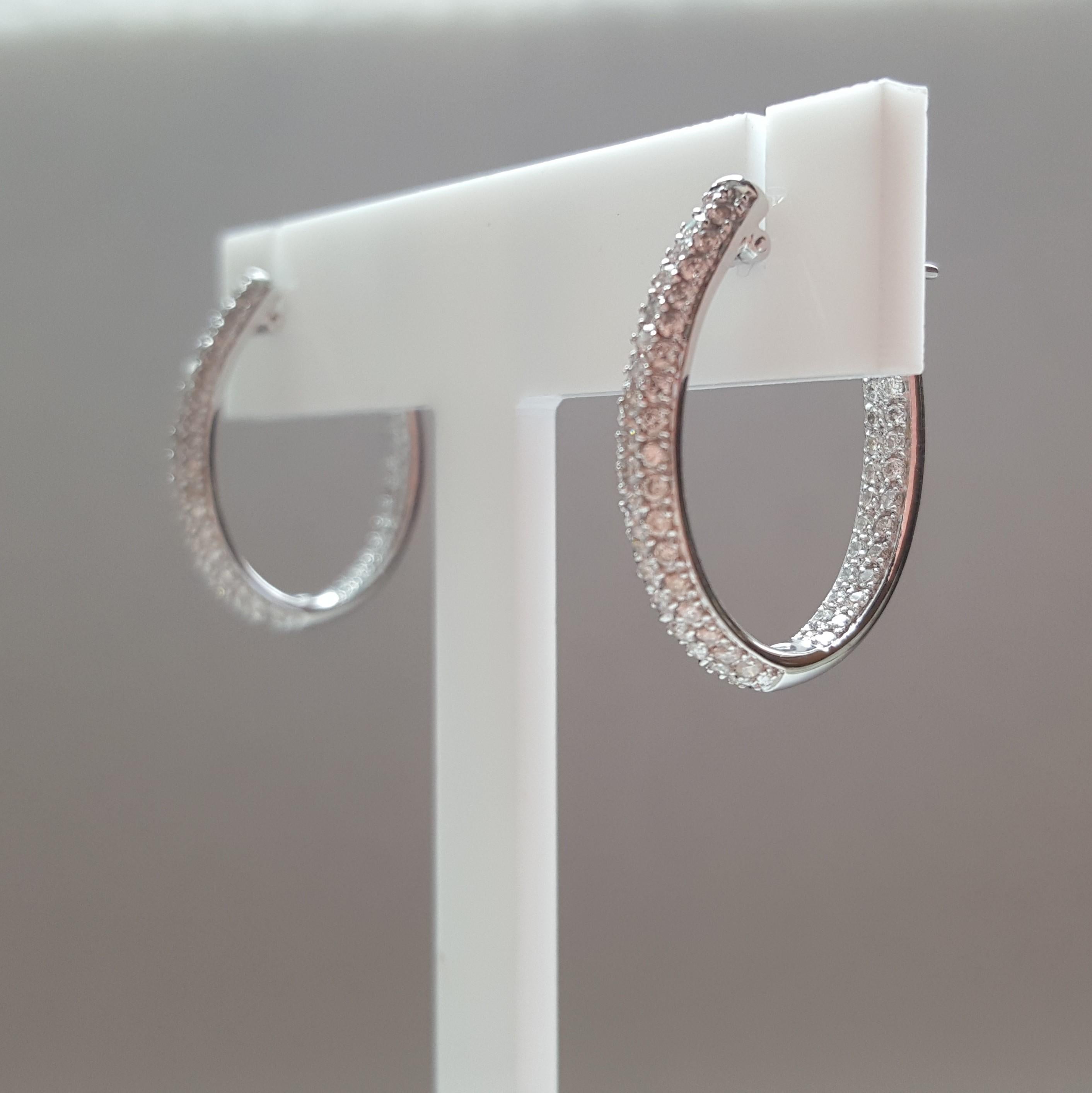 18kt white gold round brilliant diamond pave diamond hoop earrings, inside-outside style, designed by Tech Line Jewelry; these earrings are 24mm long by 3.3mm wide. The round brilliant diamonds are of good quality, H/I color, and SI in clarity.