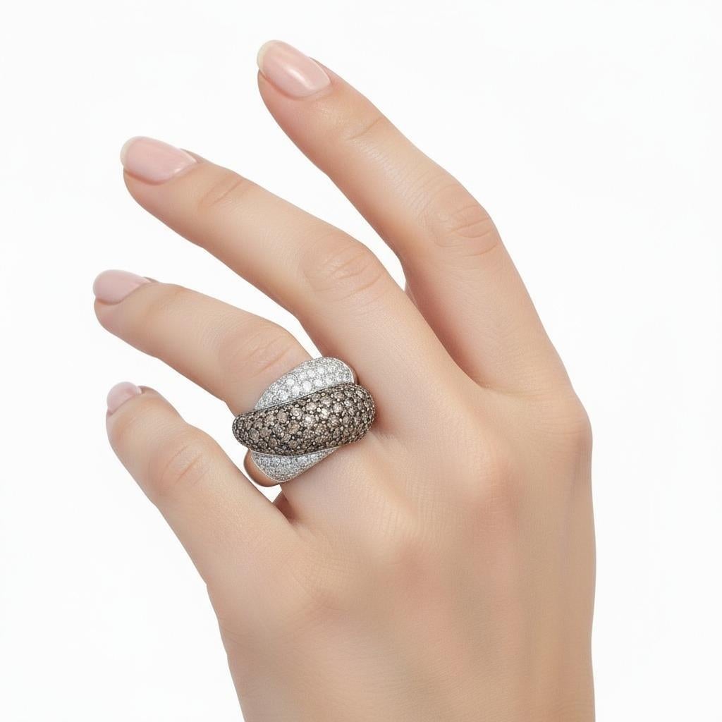 This striking crossover ring is expertly crafted in 18kt white gold, featuring a dynamic pavé of round-cut champagne and white diamonds totaling approximately 3.25 carats. The white diamonds, graded H color, add icy brilliance, while the champagne