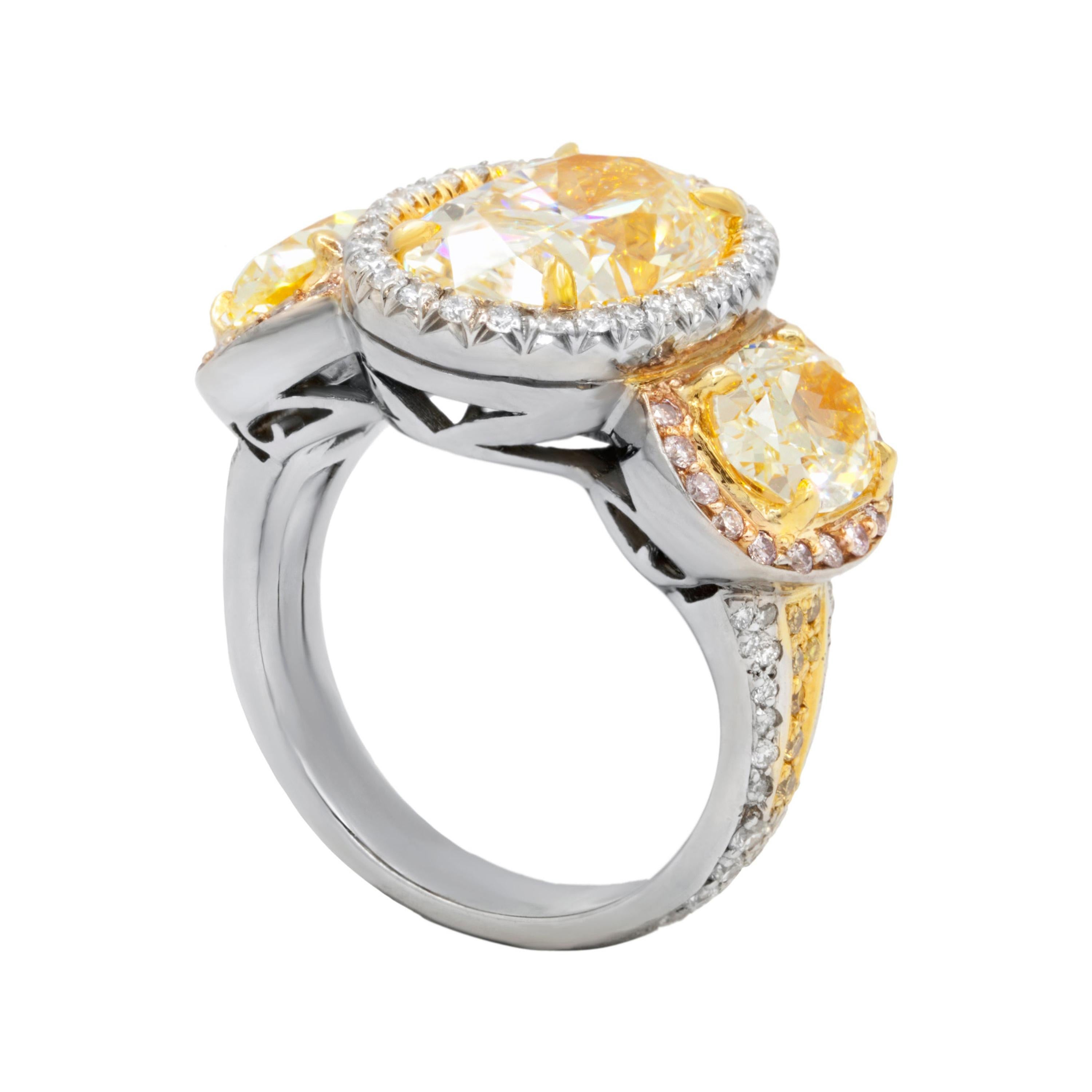 18kt white gold diamond ring featuring 4.52ct (ovc230) center fancy yellow oval diamond si1 clarity.  The ring also contains 2 oval brilliant cut diamonds weighing 2.30ct fancy yellow color vs1 clarity.  There are additional pink and white diamond