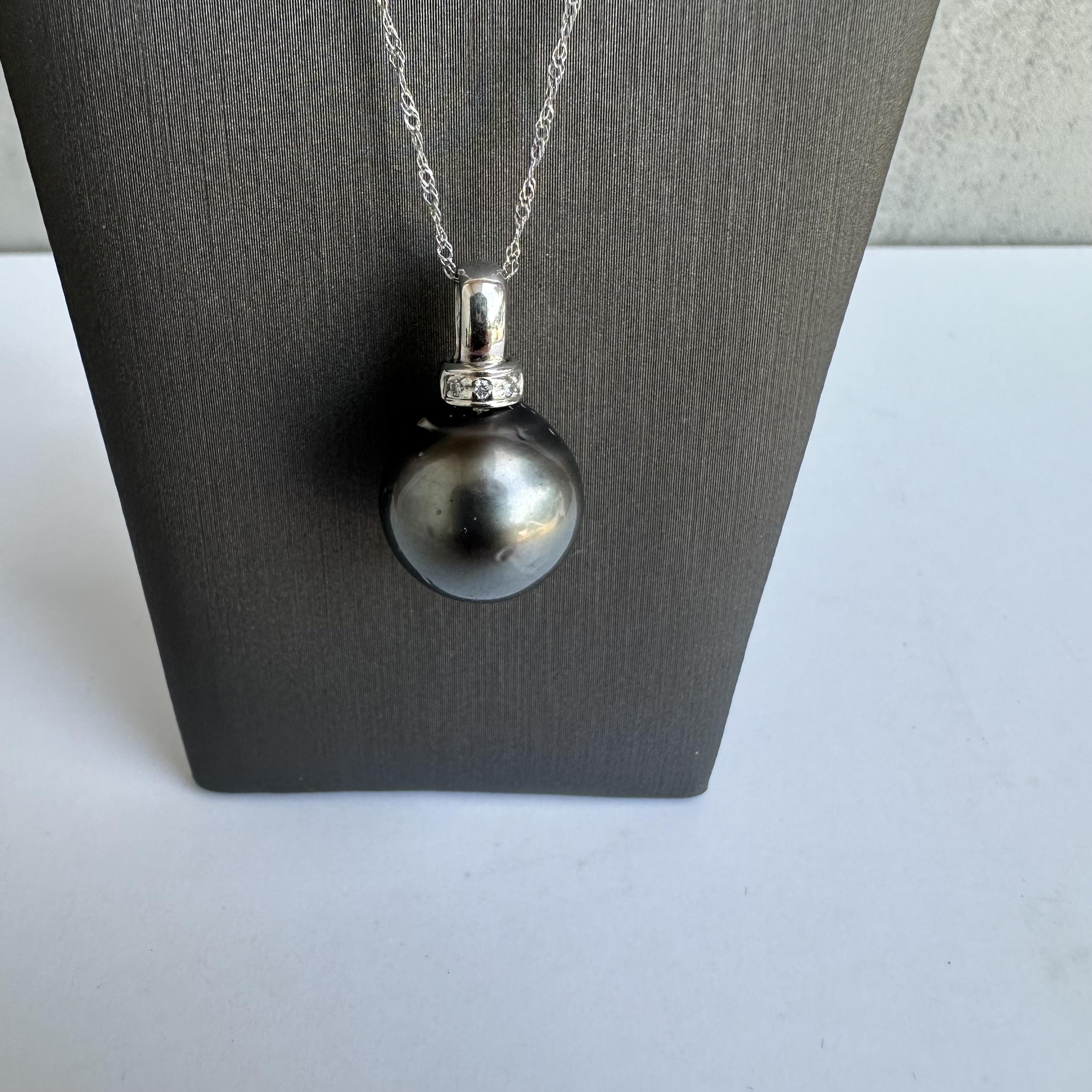 Dieses elegante Collier aus Tahiti-Perlen und Diamanten aus 18-karätigem Weißgold wertet Ihre Schmucksammlung auf. Mit einer auffälligen 13,1 mm großen schwarzen Tahiti-Perle und 0,02 Karat natürlichen, runden Diamanten von GH SI, die in die