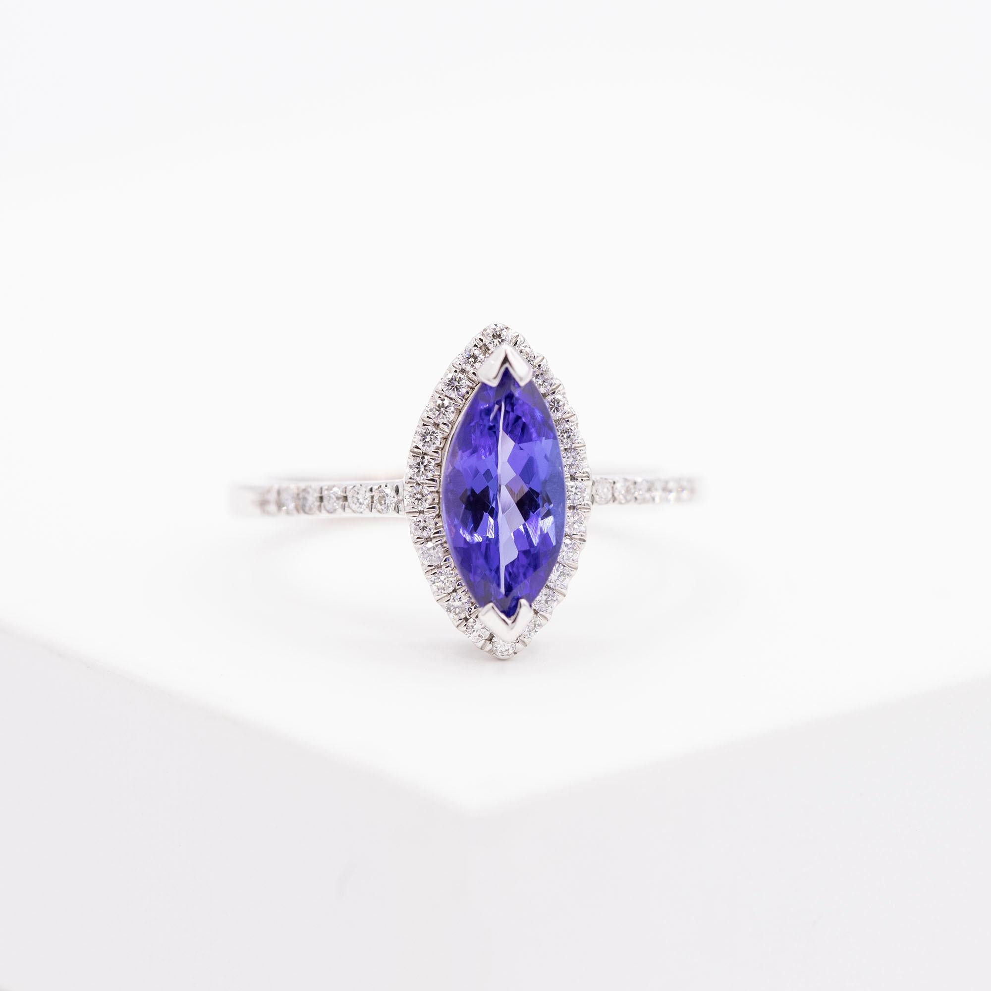 18kt White Gold Tanzanite & Diamond Ring. The marquise cut tanzanite weighs 1.20 approximately. The halo has 24 round diamonds and 12 round diamonds in  the shank. The diamonds have a total carat weight of .27 carats. The ring is a size 6 1/4.