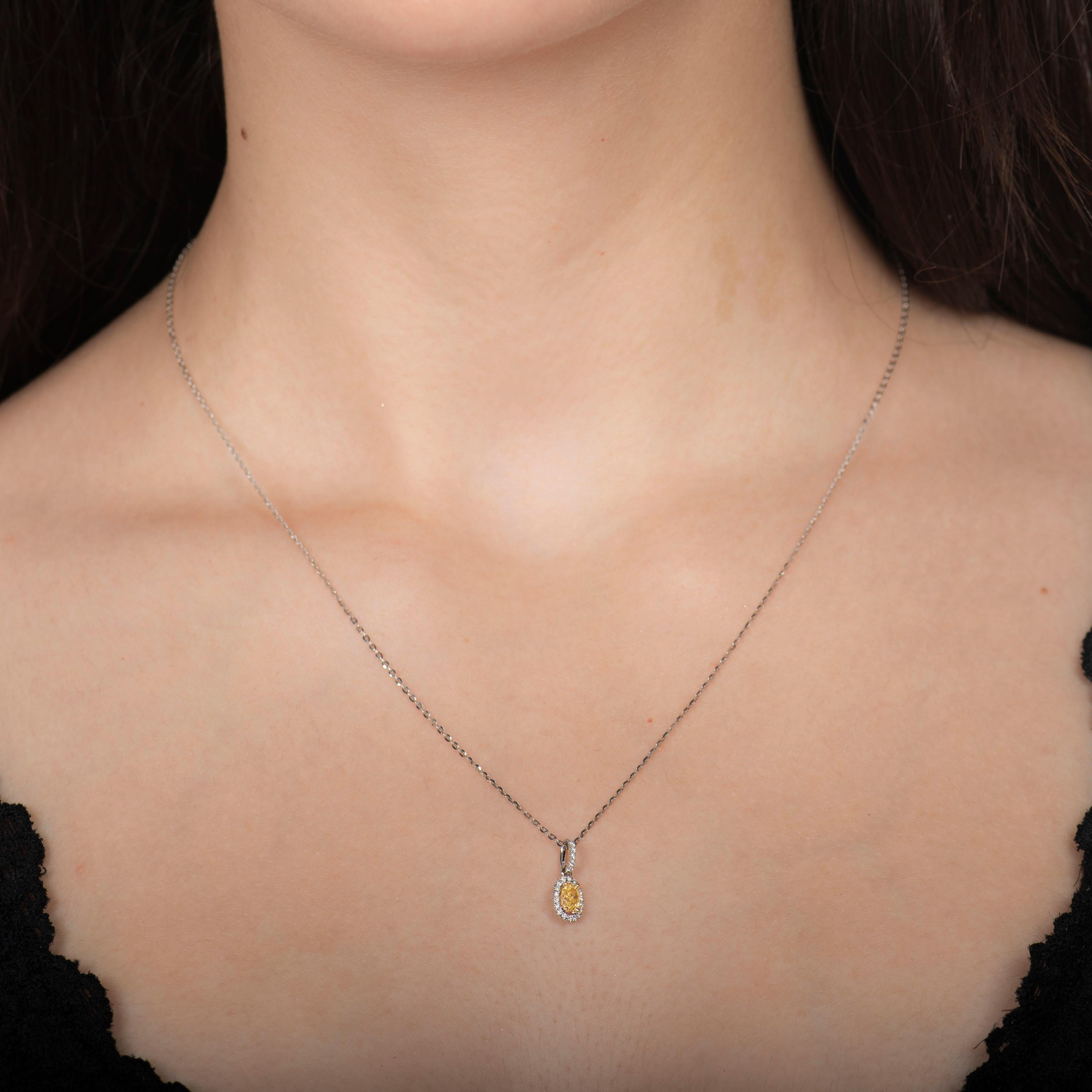 This 18kt white gold pendant features a 0.33ct natural yellow oval diamond set in 18kt yellow gold prongs. The surrounding round brilliant cut diamonds have a 0.10ct total weight, including a diamond accented bail. The pendant is simplistic but adds