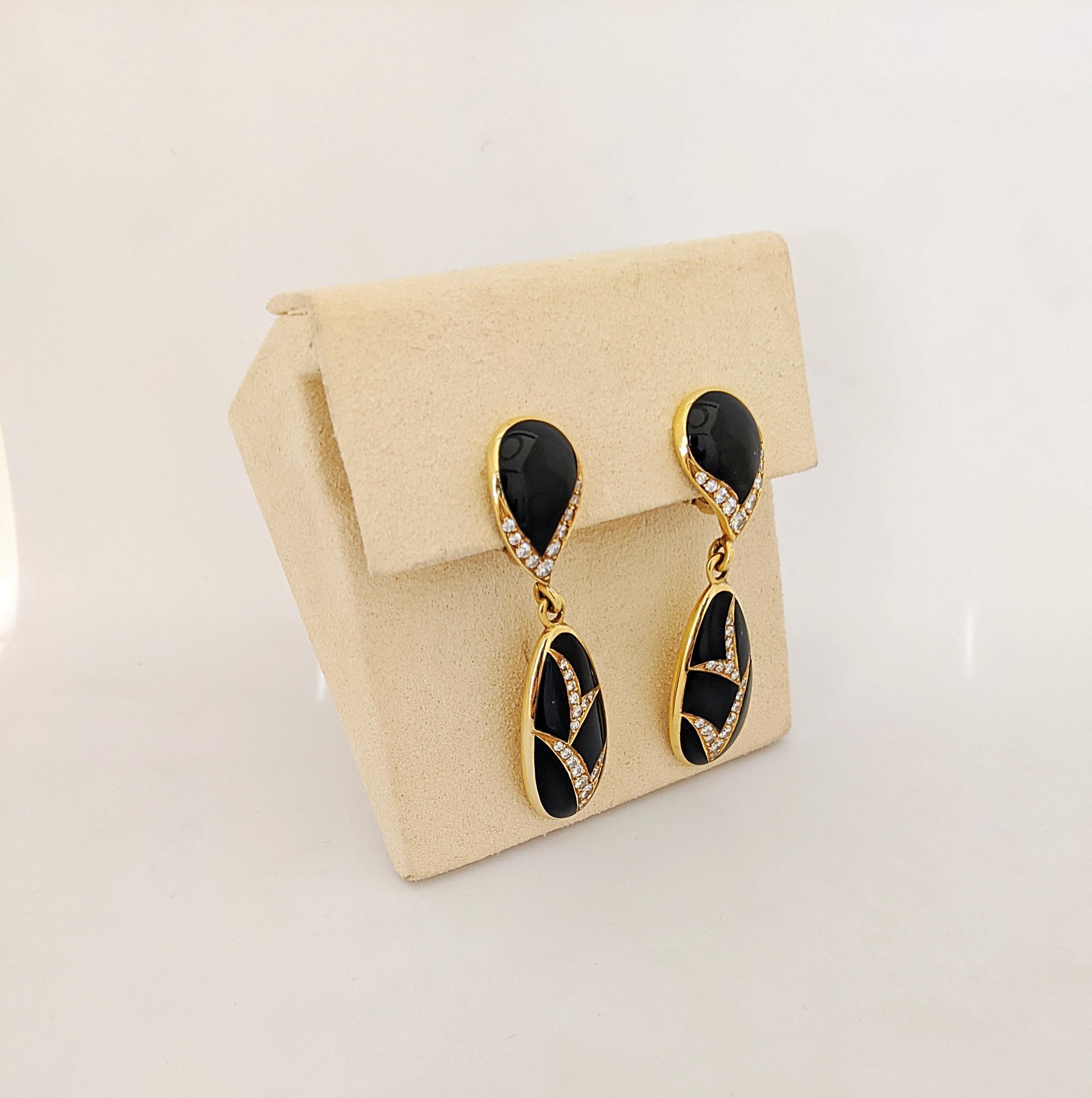 A very classic pair of 18 Karat Yellow Gold hanging drop earrings with Diamonds and Black Onyx. The earrings are designed with 2 sections . The top section features Black Onyx in a pear shape outlined with round Brilliant Cut diamonds. The bottom
